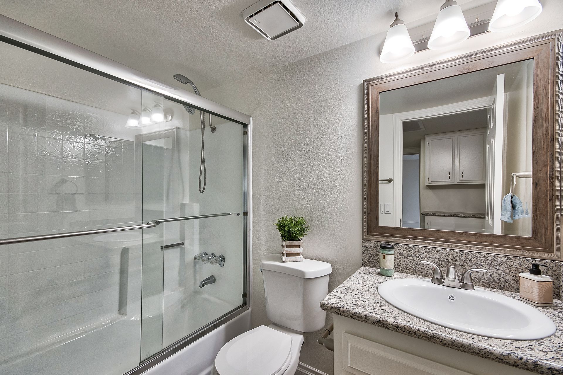 A bathroom with a toilet , sink , shower and mirror