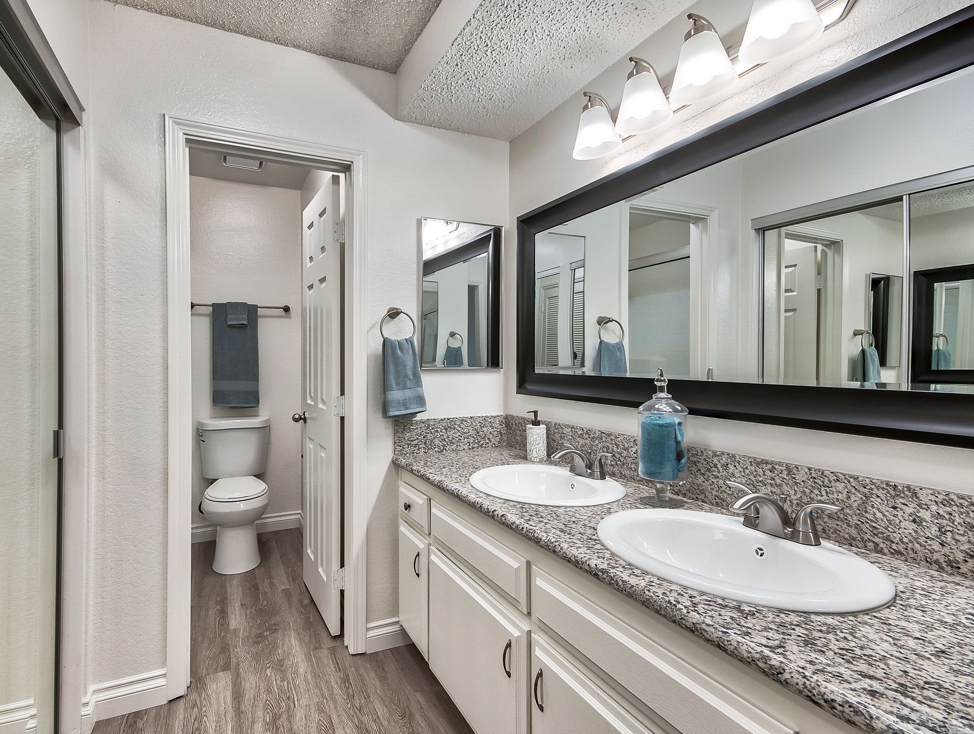 A bathroom with two sinks , a toilet , and a large mirror.