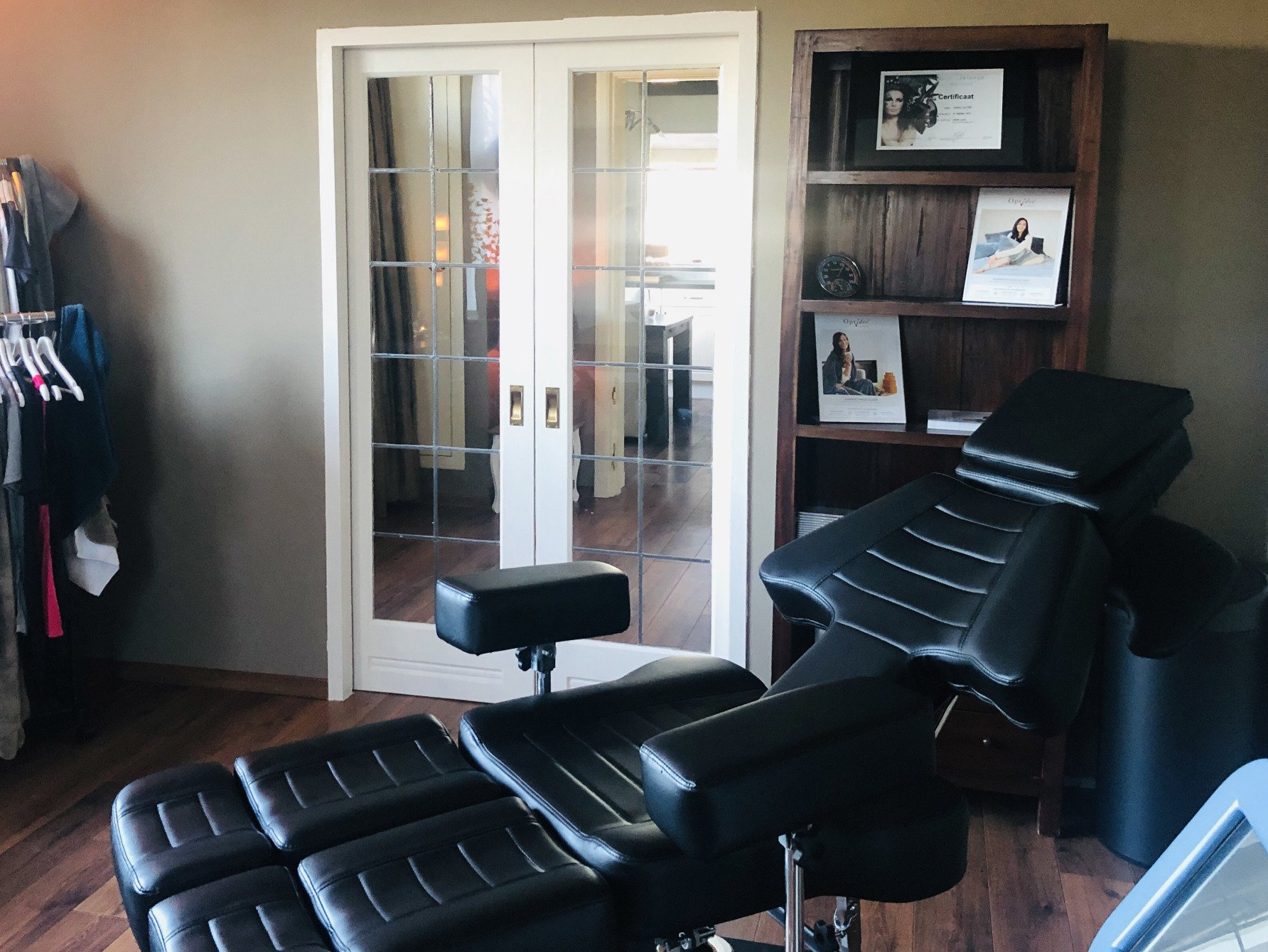 In een kamer met op de achtergrond een houten boekenkast en dubbele glazen deuren staat een zwarte behandeltafel.