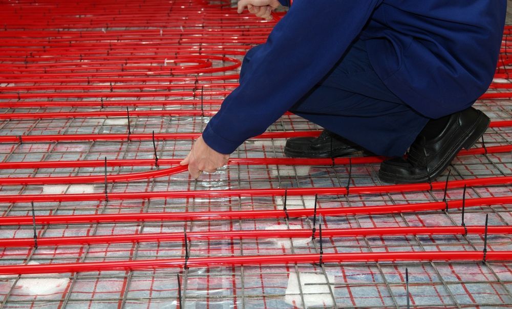 Person Installing Red Radiant Floor Heating Tubes — Illawarra Underfloor Heating In Ulladulla, NSW