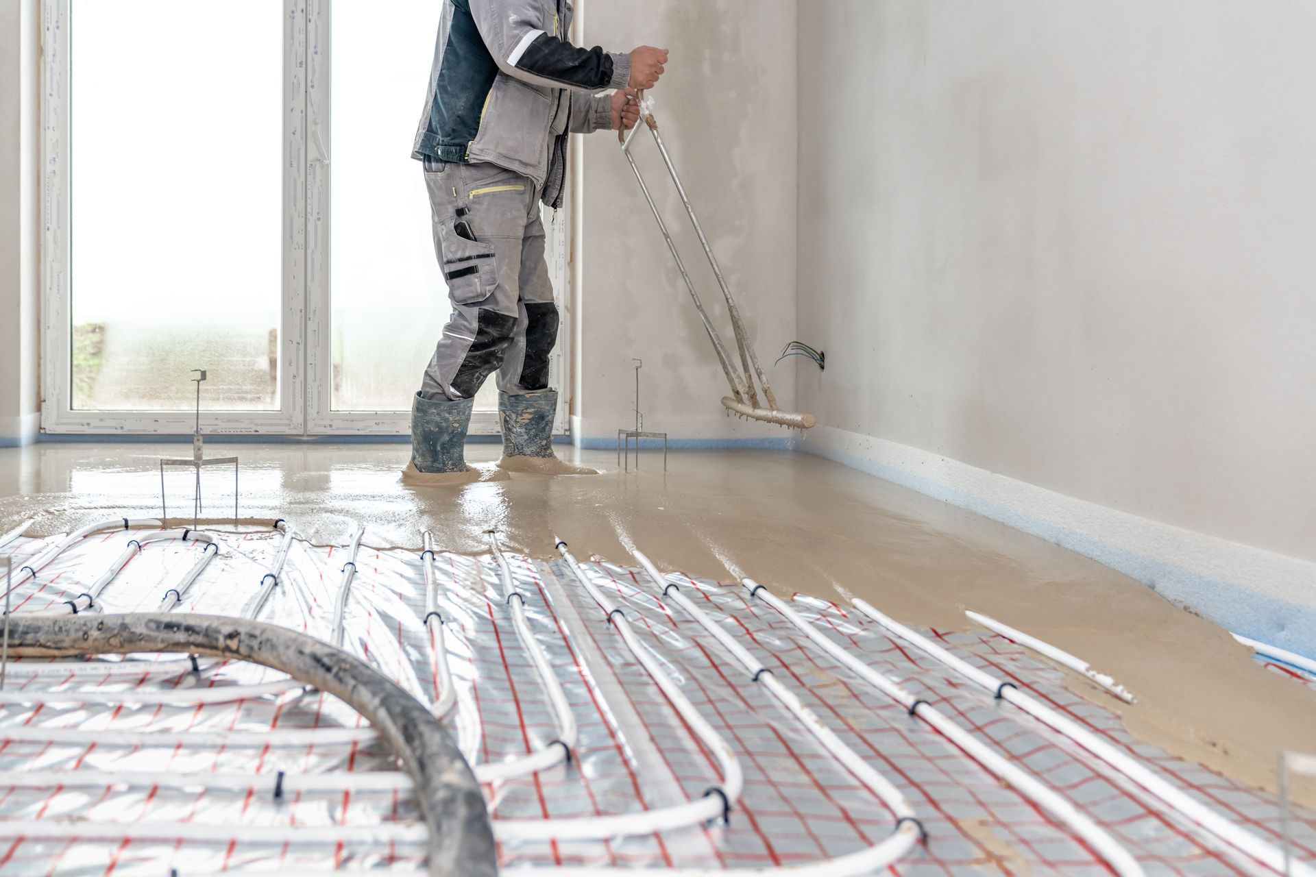 Worker Smoothing Wet Concrete Floor with Underfloor Heating System — Illawarra Underfloor Heating In Bellambi, NSW