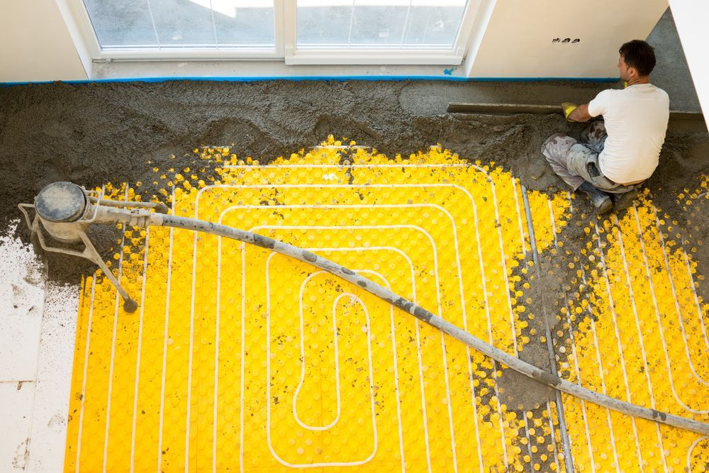 Man Leveling Concrete Over Yellow Radiant Floor Heating Tubes — Illawarra Underfloor Heating In Kiama, NSW