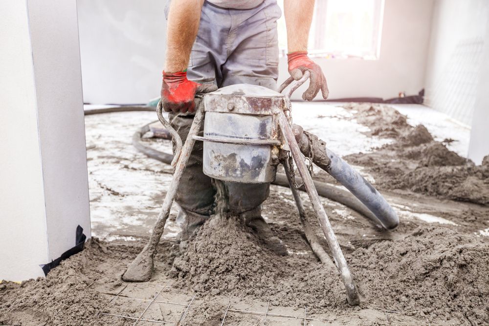 Construction Worker Using a Machine to Spread Wet Cement — Illawarra Underfloor Heating In Kiama, NSW
