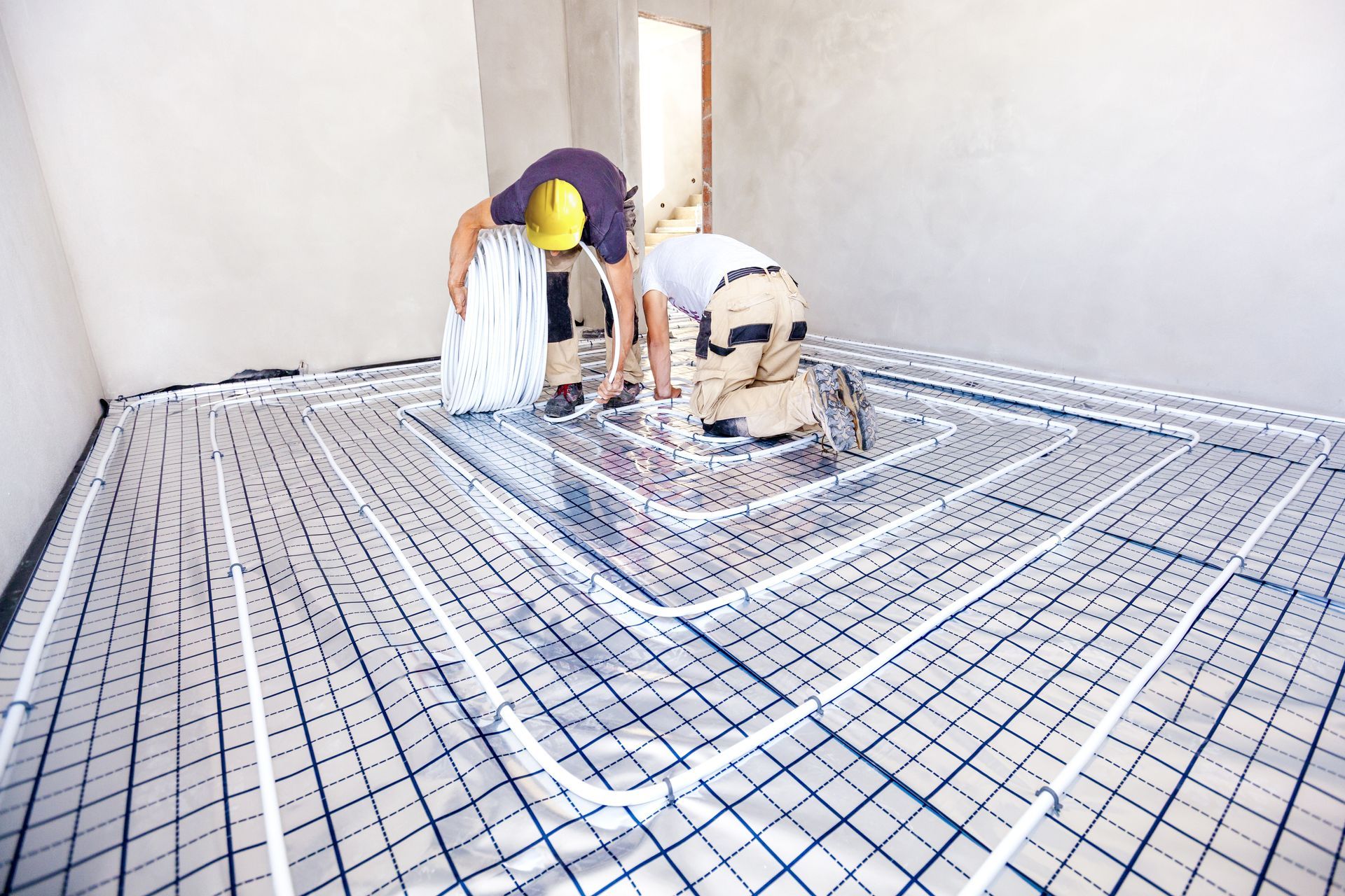 Two Construction Workers Installing Radiant Floor Heating in A Room — Illawarra Underfloor Heating In Shellharbour, NSW