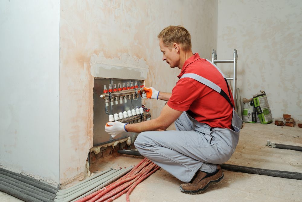A Man in Work Clothes Installs Plumbing — Illawarra Underfloor Heating In Kiama, NSW