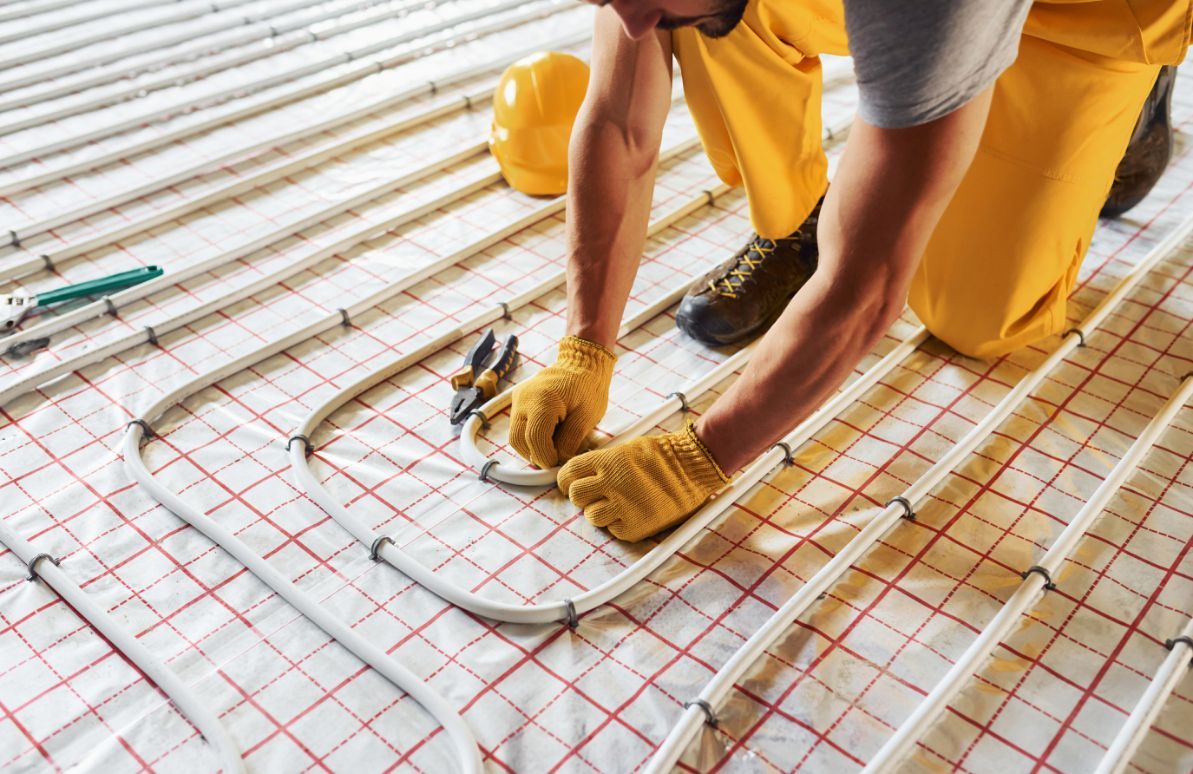 Man in Yellow Work Clothes Installs Underfloor Heating Tubes  — Illawarra Underfloor Heating In Kiama, NSW