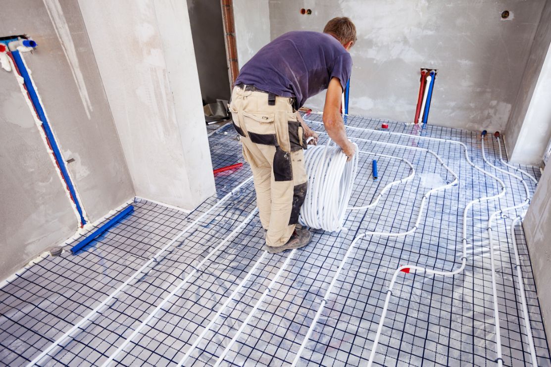 A Construction Worker Installs Underfloor Heating Coils in A Room — Illawarra Underfloor Heating In Ulladulla, NSW
