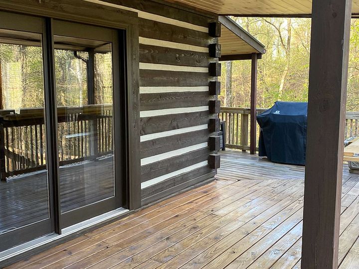 A log cabin with a large deck and sliding glass doors.
