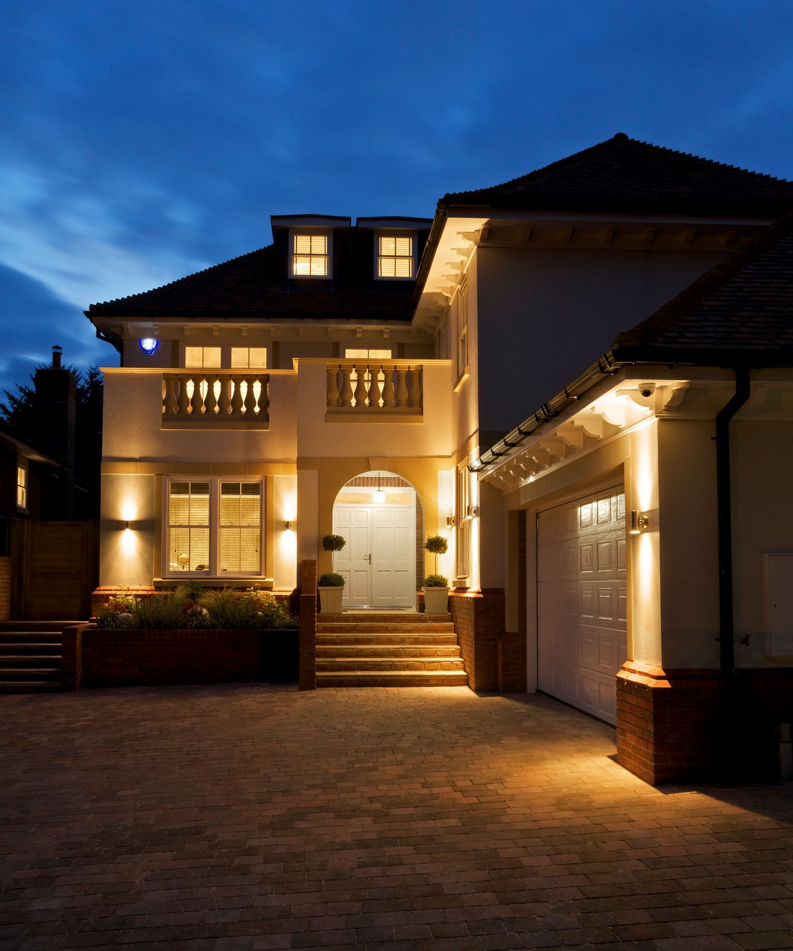 a late evening exterior view of a luxury new home with all internal and outside lights switched on. 