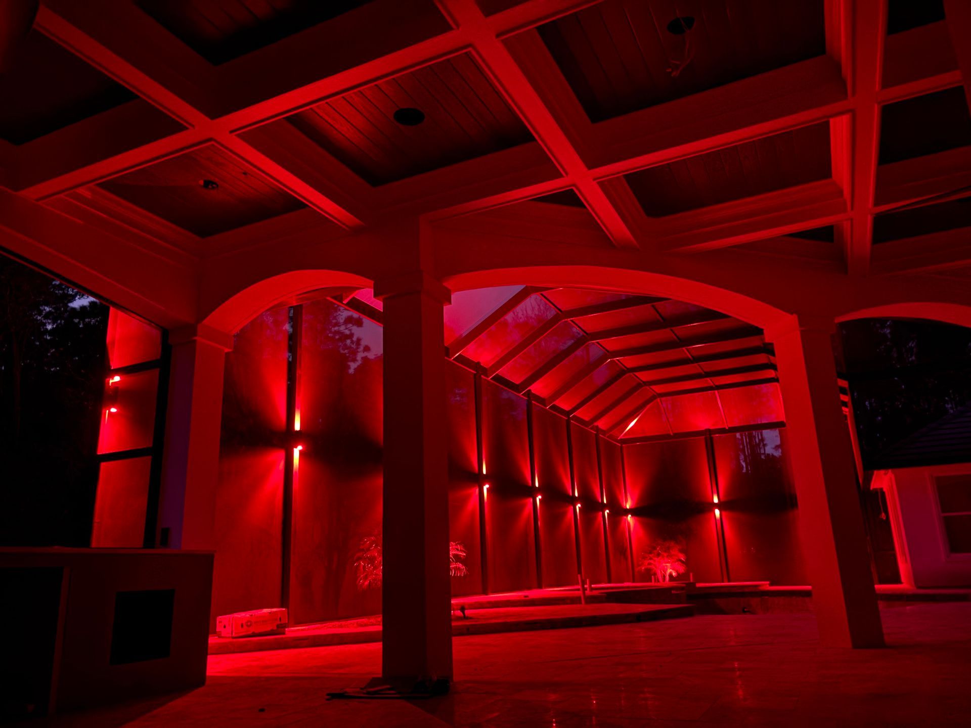 Red-lit indoor space with columns, arches, and a paneled ceiling. The building appears unfinished.