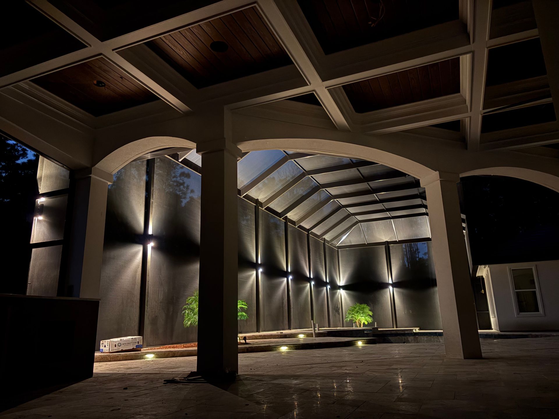 Exterior architectural space with arched openings, recessed lighting, and dark walls.