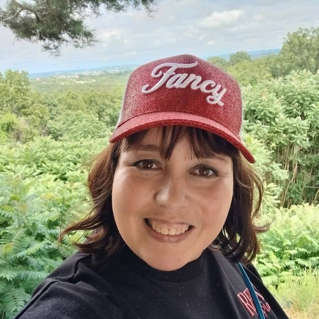 woman taking a selfie in nature wearing a red hat