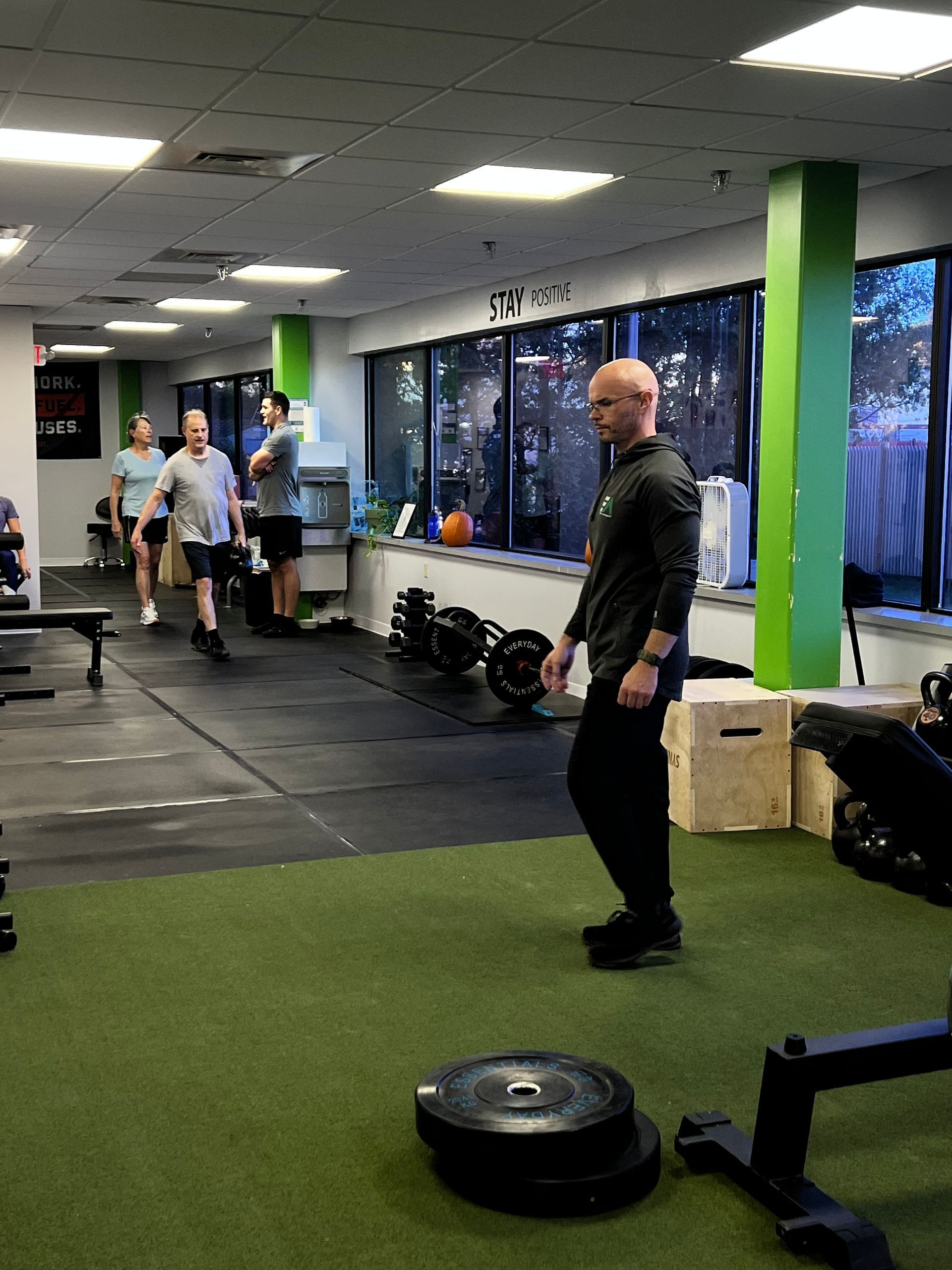 A man is squatting on a bench in a gym.