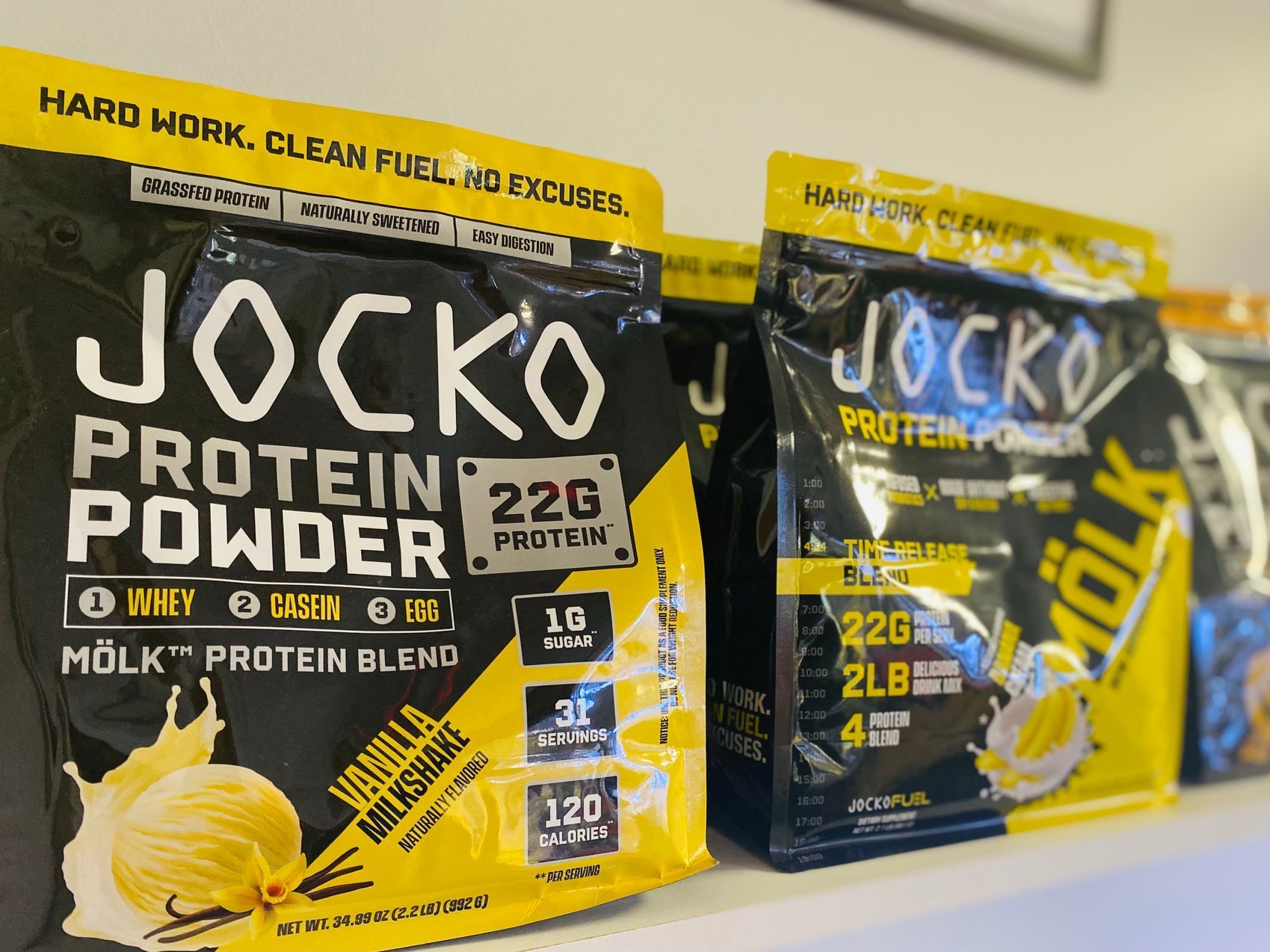 Two bags of jocko protein powder are sitting on a shelf.