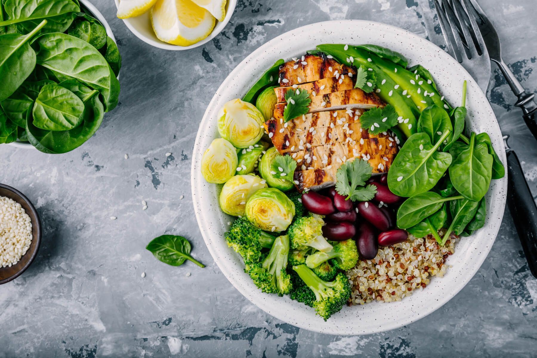 A bowl of chicken , broccoli , beans , rice and spinach on a table.