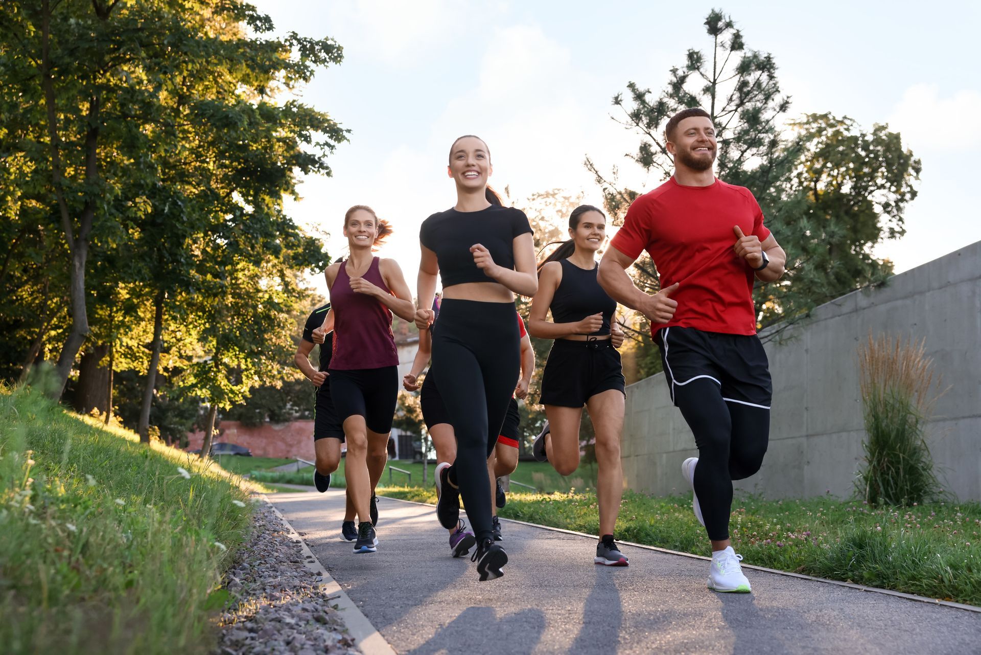 A group of people are running on a path in a park.