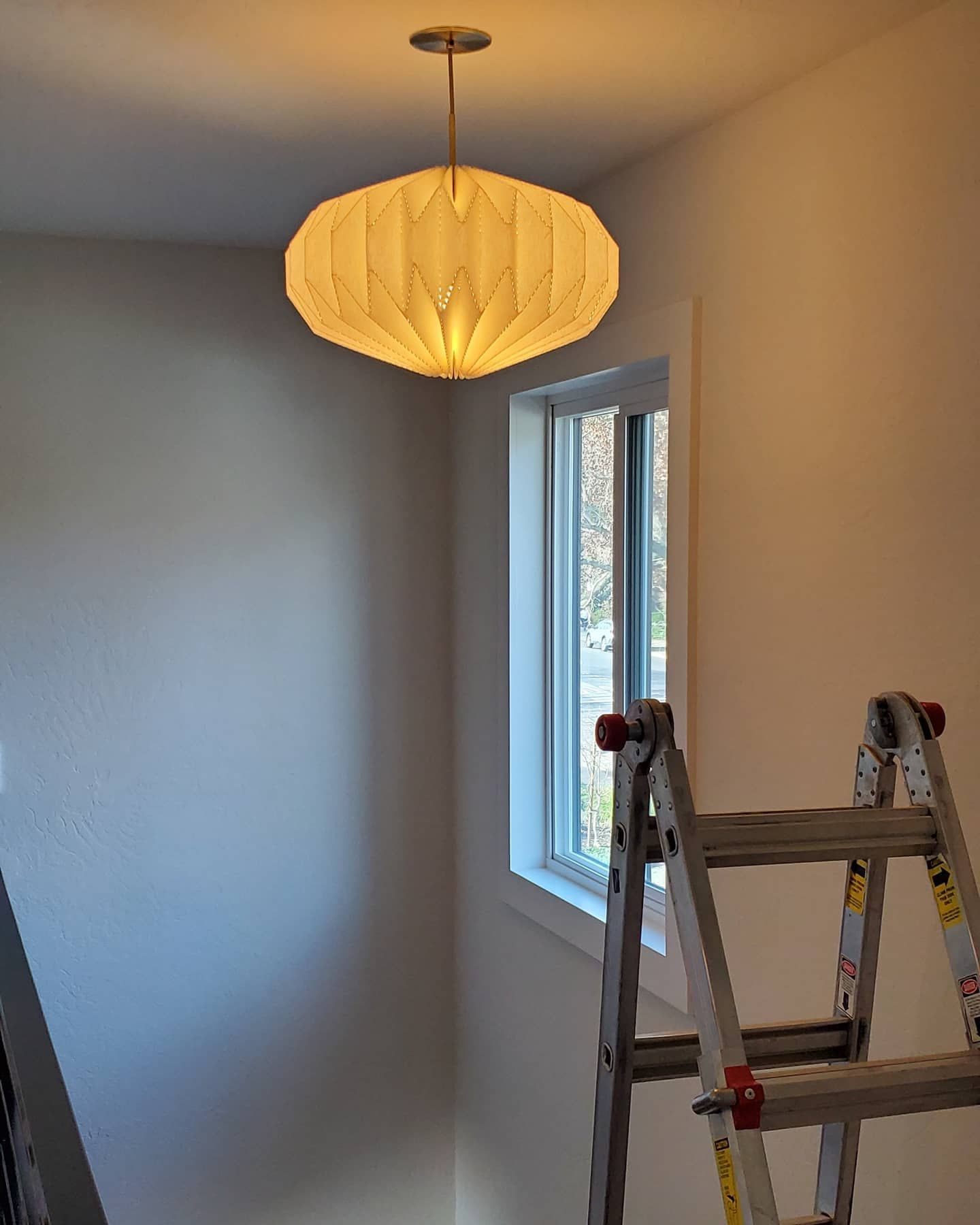 Pendant light fixture hangs near a window. A ladder leans against the wall.