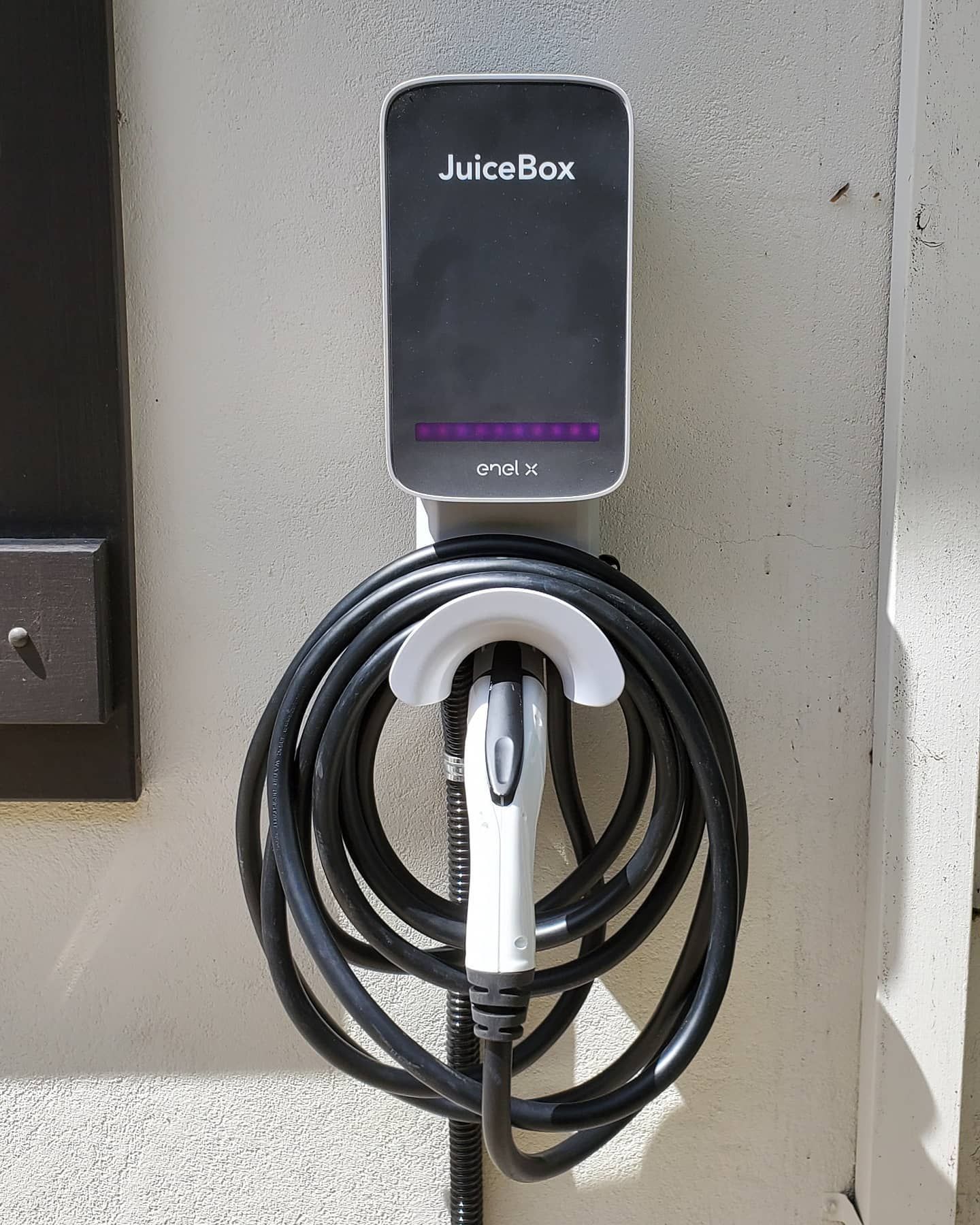 JuiceBox EV charger mounted on a light-colored wall, cable coiled below.