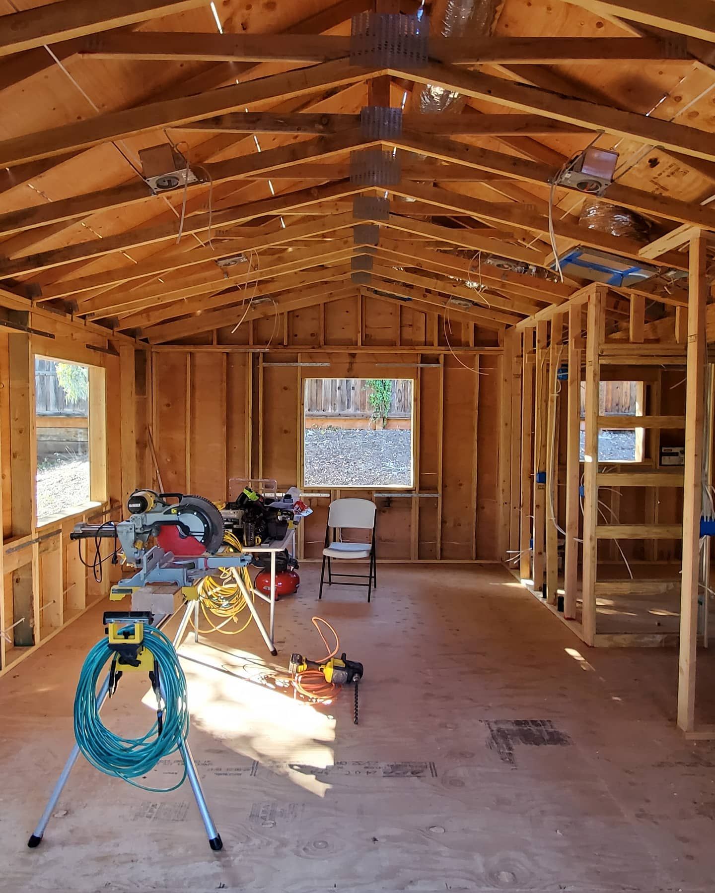 Interior view of a wooden framed structure under construction with tools and a window.