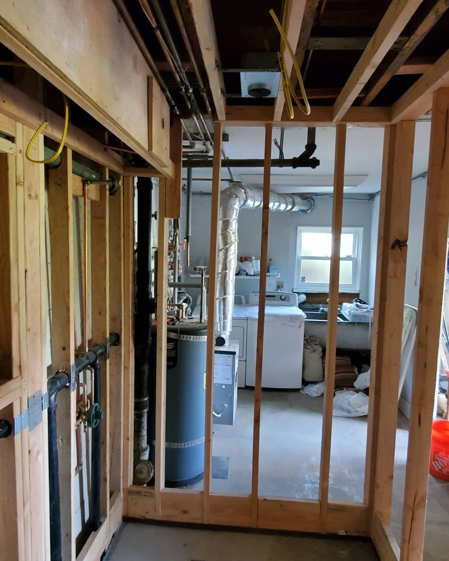 Framing for interior walls, showing pipes and laundry room with window, construction.