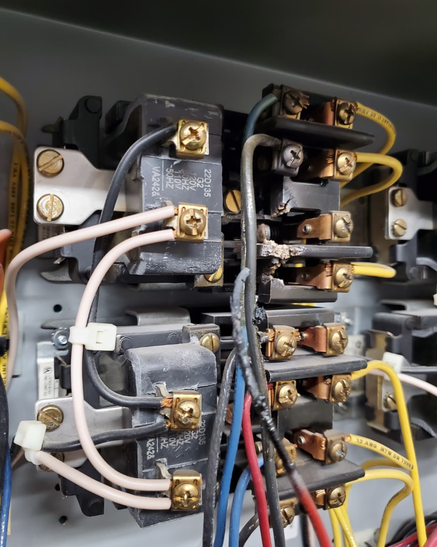Electrical control panel with wires connected to black components; some wires are damaged.