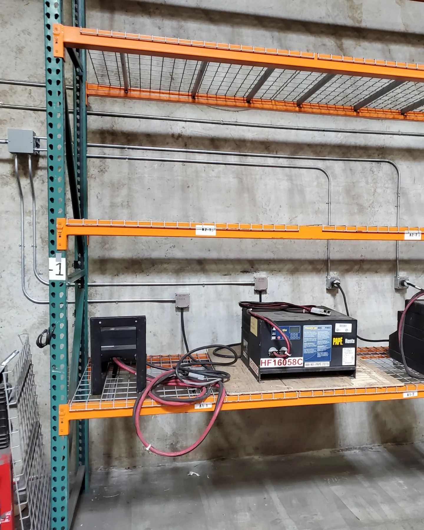 Orange warehouse shelving holding electrical equipment and wiring.