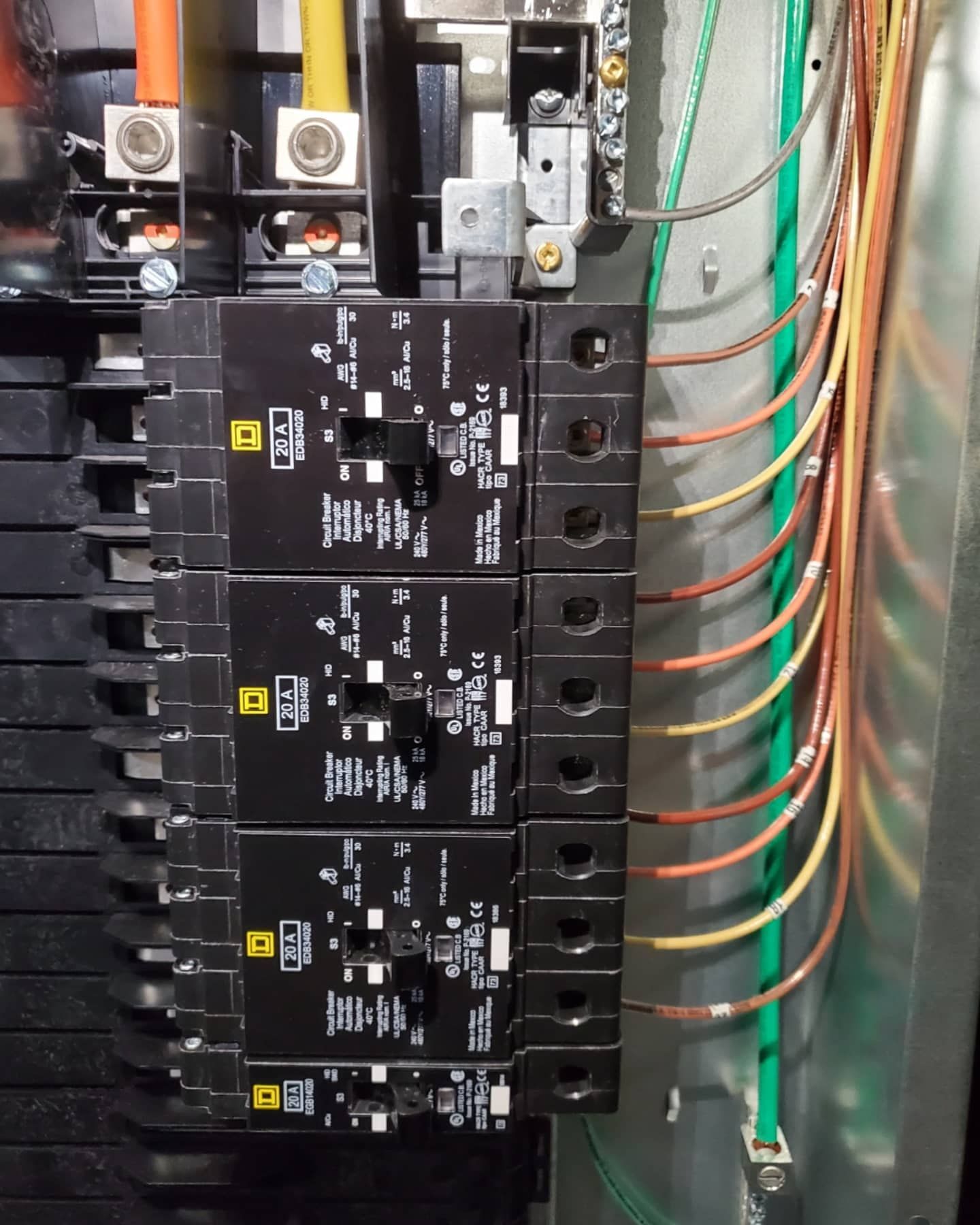 Electrical panel with black circuit breakers and wires of various colors.