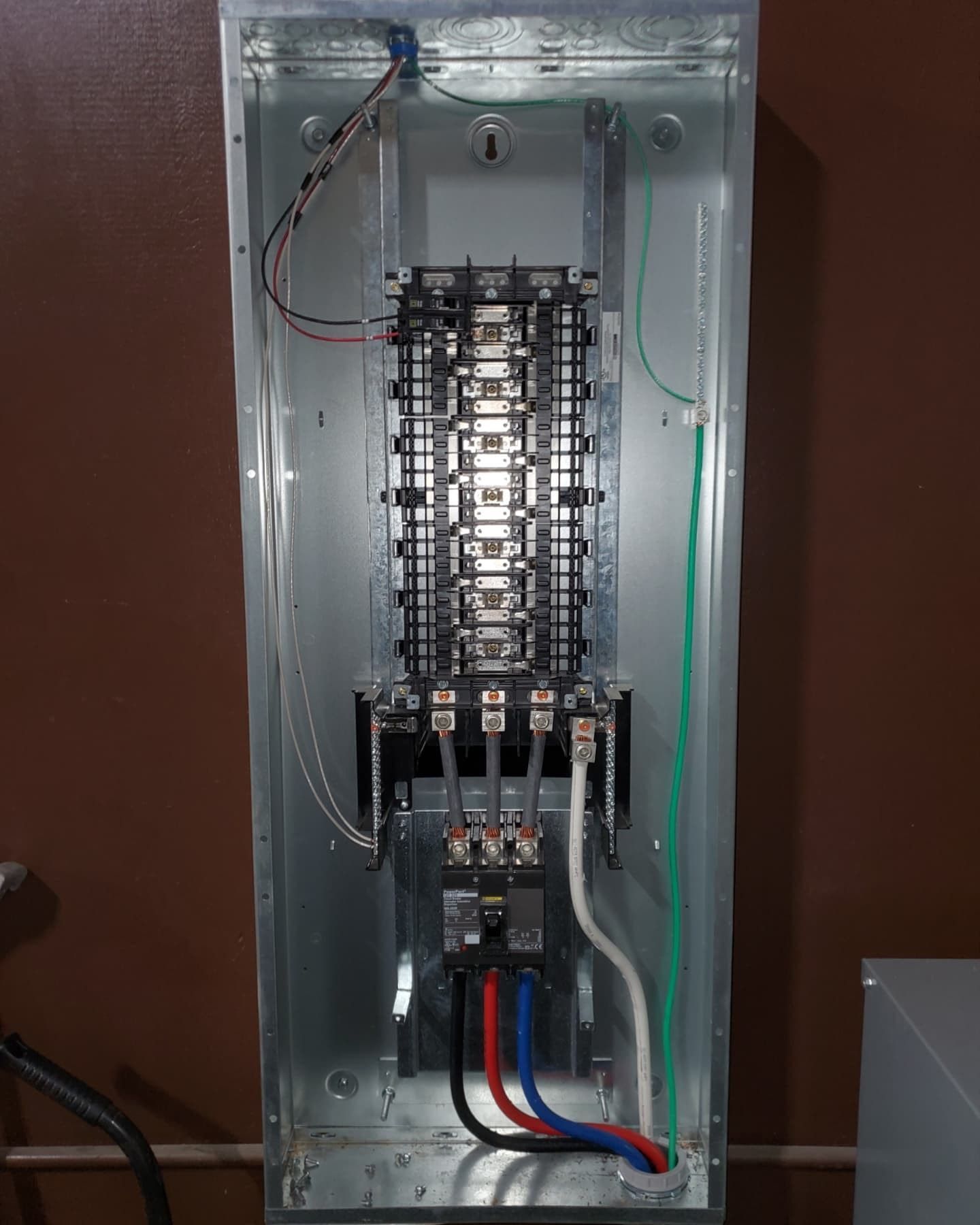 Open electrical panel with wires & circuit breakers. Blue, red, and black wires are connected to a bottom breaker.