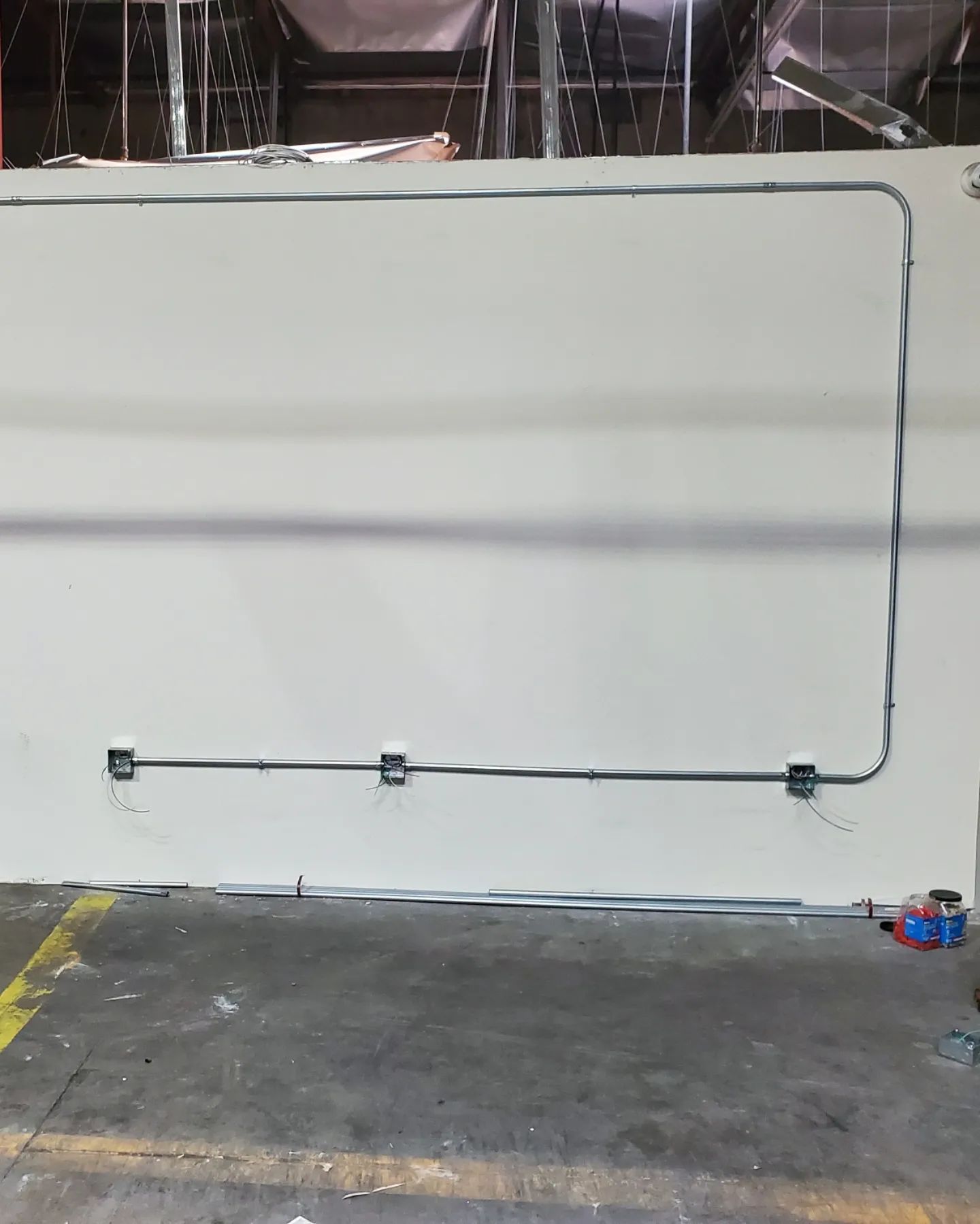 Electrical conduit and boxes installed on a white wall in a construction site.