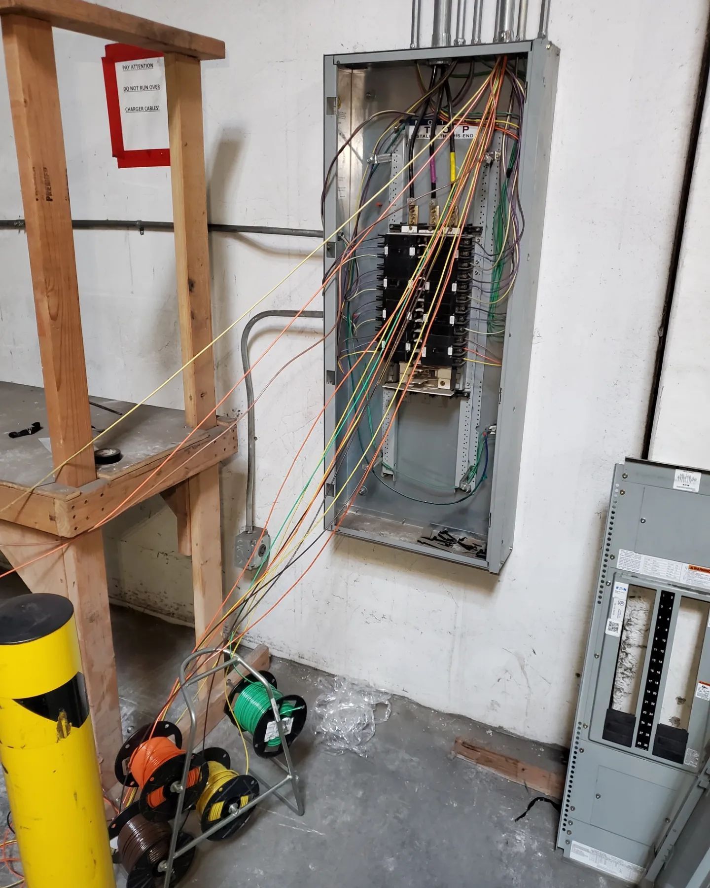 Electrical panel with wires, tools, and spools, mounted on a wall.