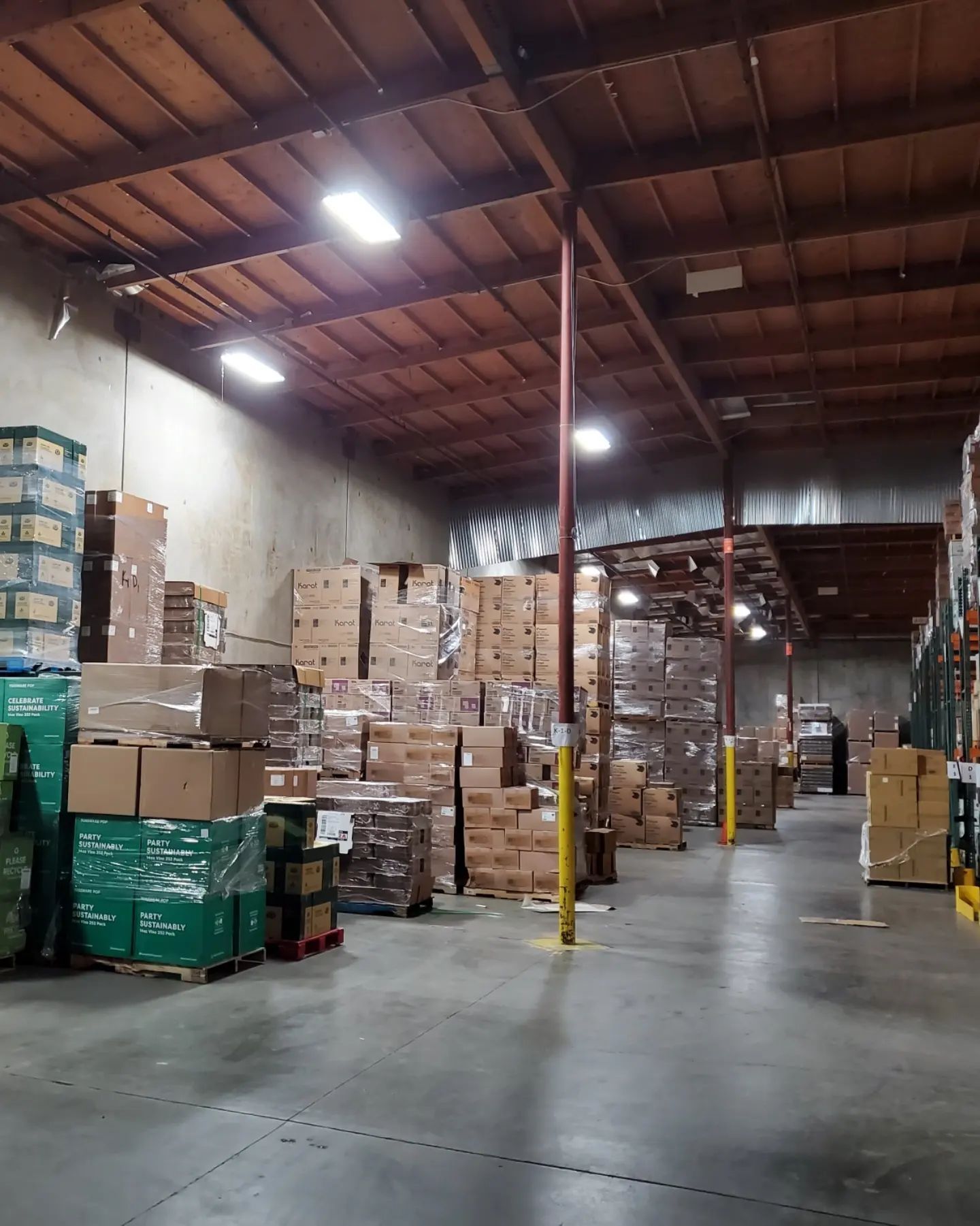 Warehouse interior with stacks of boxes and pallets filled with goods.