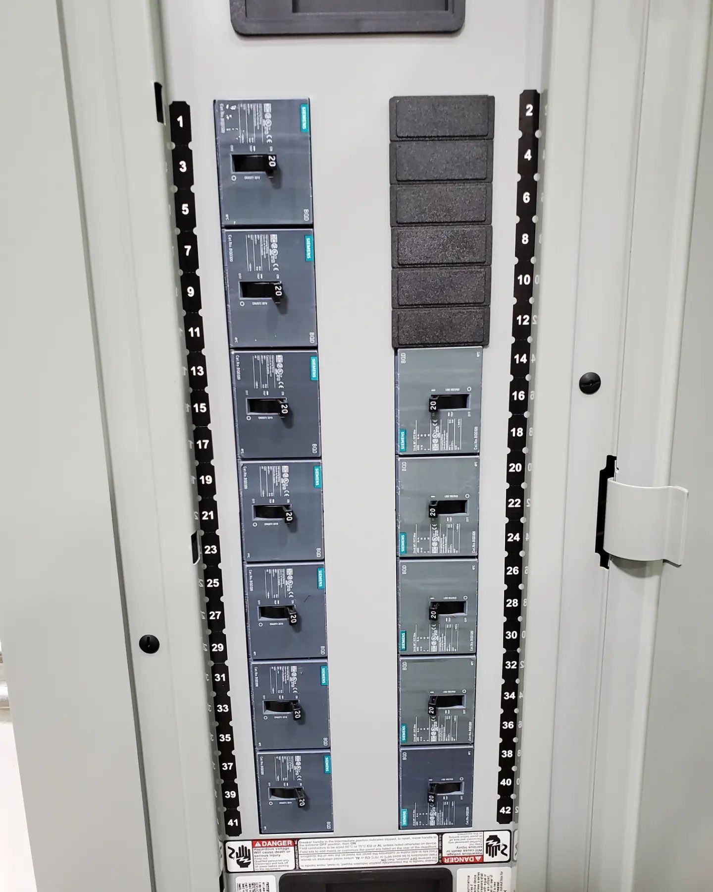 Electrical panel with circuit breakers. Two columns of breakers, a blank column, and numbered labels.