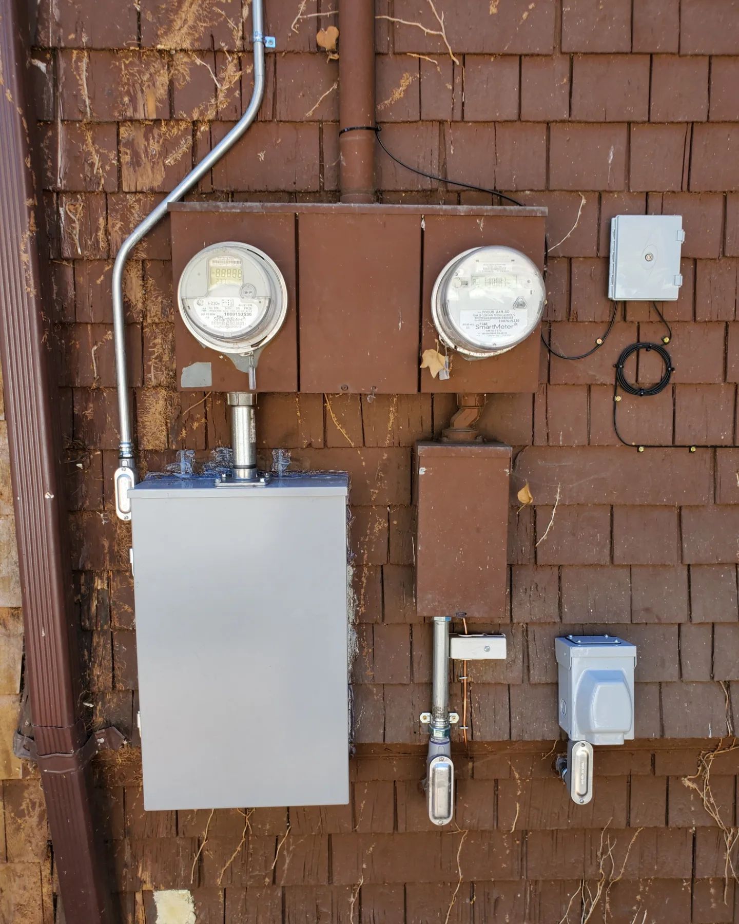 Electrical meters and components mounted on a brown wall.