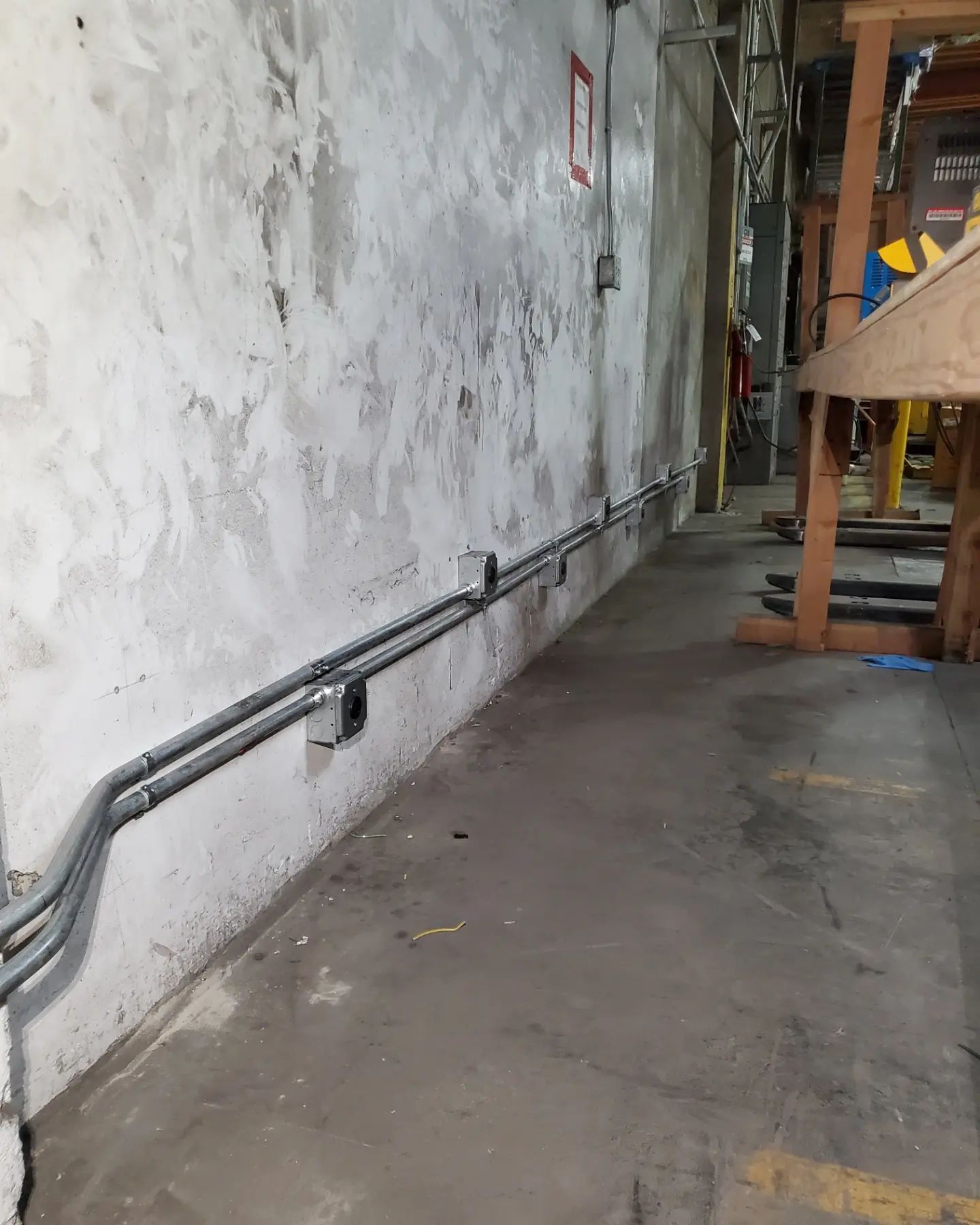 Concrete wall with electrical conduit running along the base; a concrete floor extends in front.