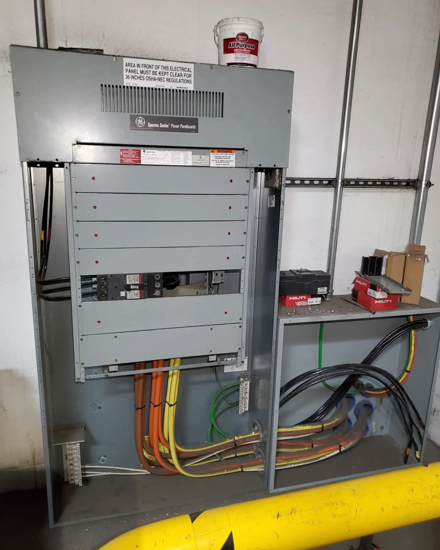 Electrical panel with open cover, wires, and conduit.