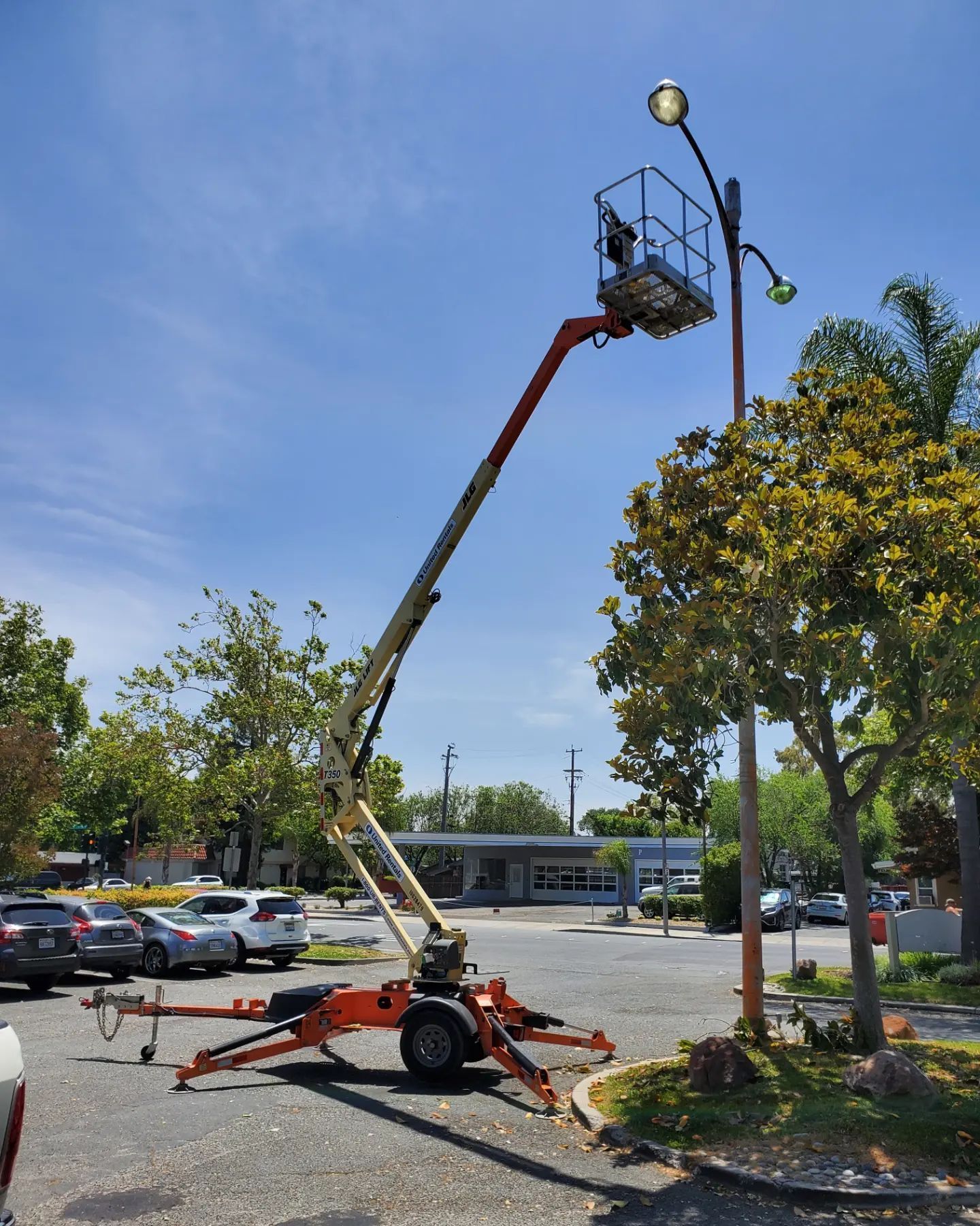 Person in lift bucket working on a street light in a parking lot.
