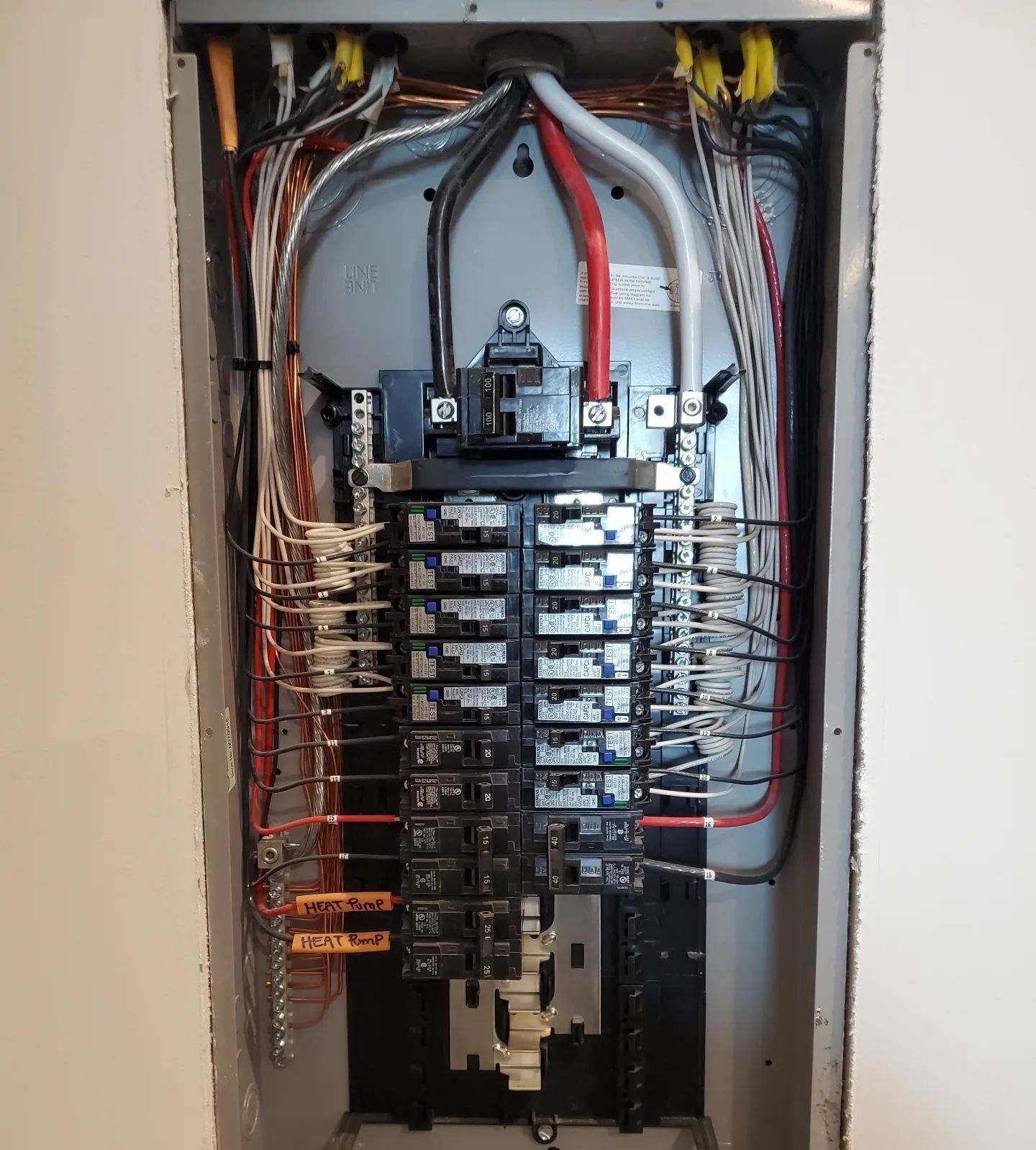 Electrical panel with rows of circuit breakers and wiring. Copper wires connect to breakers.