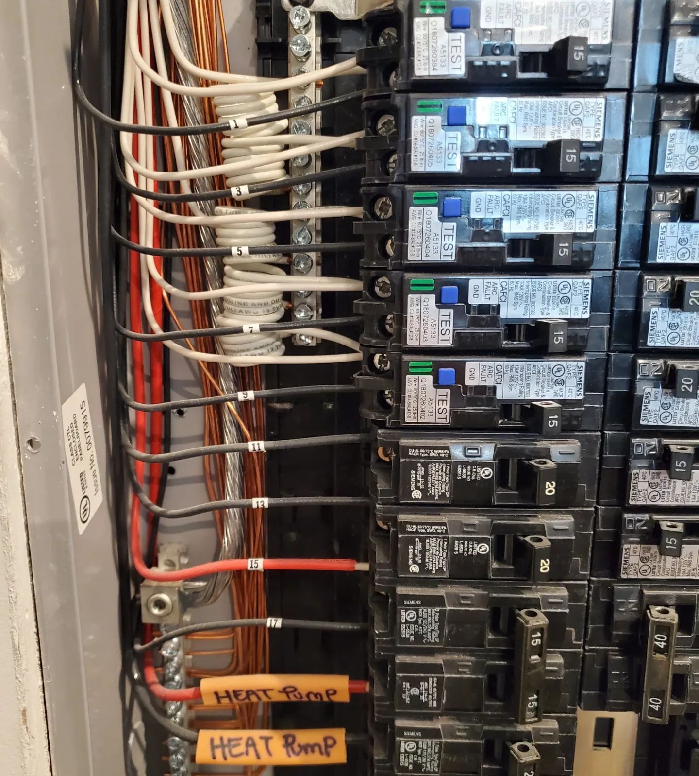 Electrical panel with wires connected to circuit breakers; labels indicate 