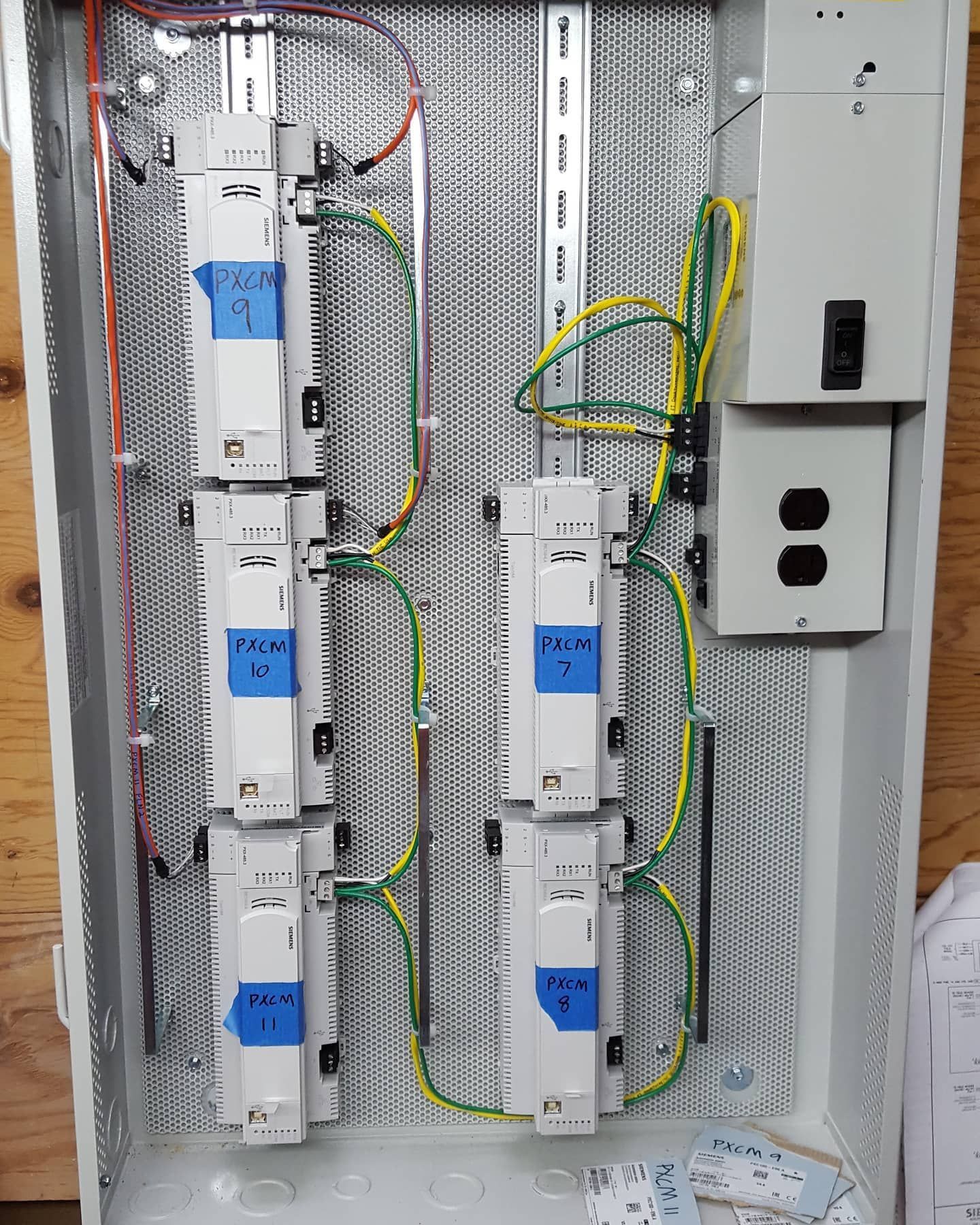 Electrical panel with circuit breakers and wiring. Ground wires are green/yellow.