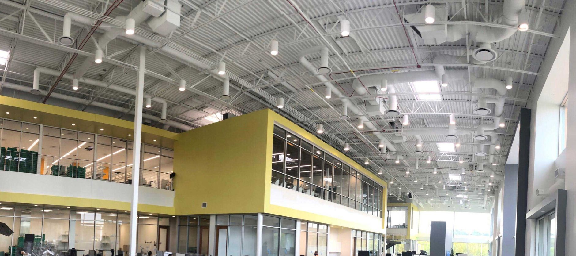 Interior of a modern building with a high, white ceiling and yellow accents.