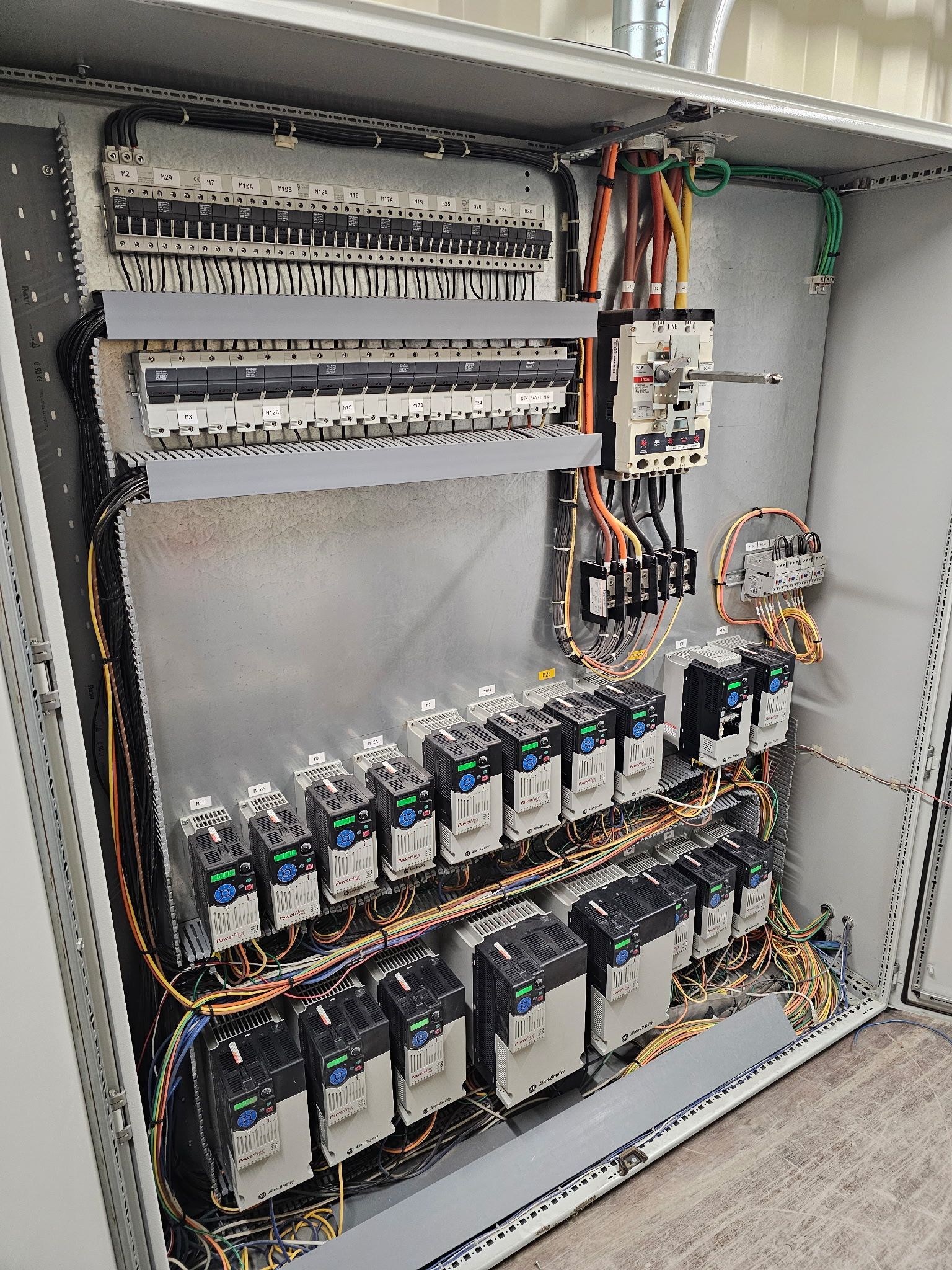 Electrical panel with circuit breakers, wires, and switches inside a metal enclosure.