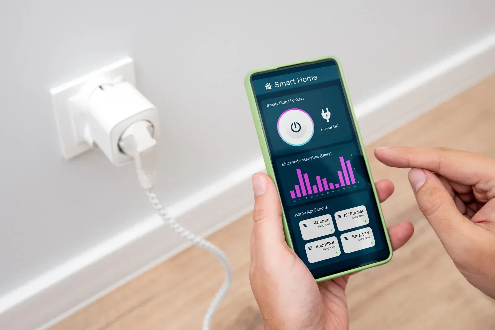 Person using smartphone to control smart plug; app displays energy usage graph.