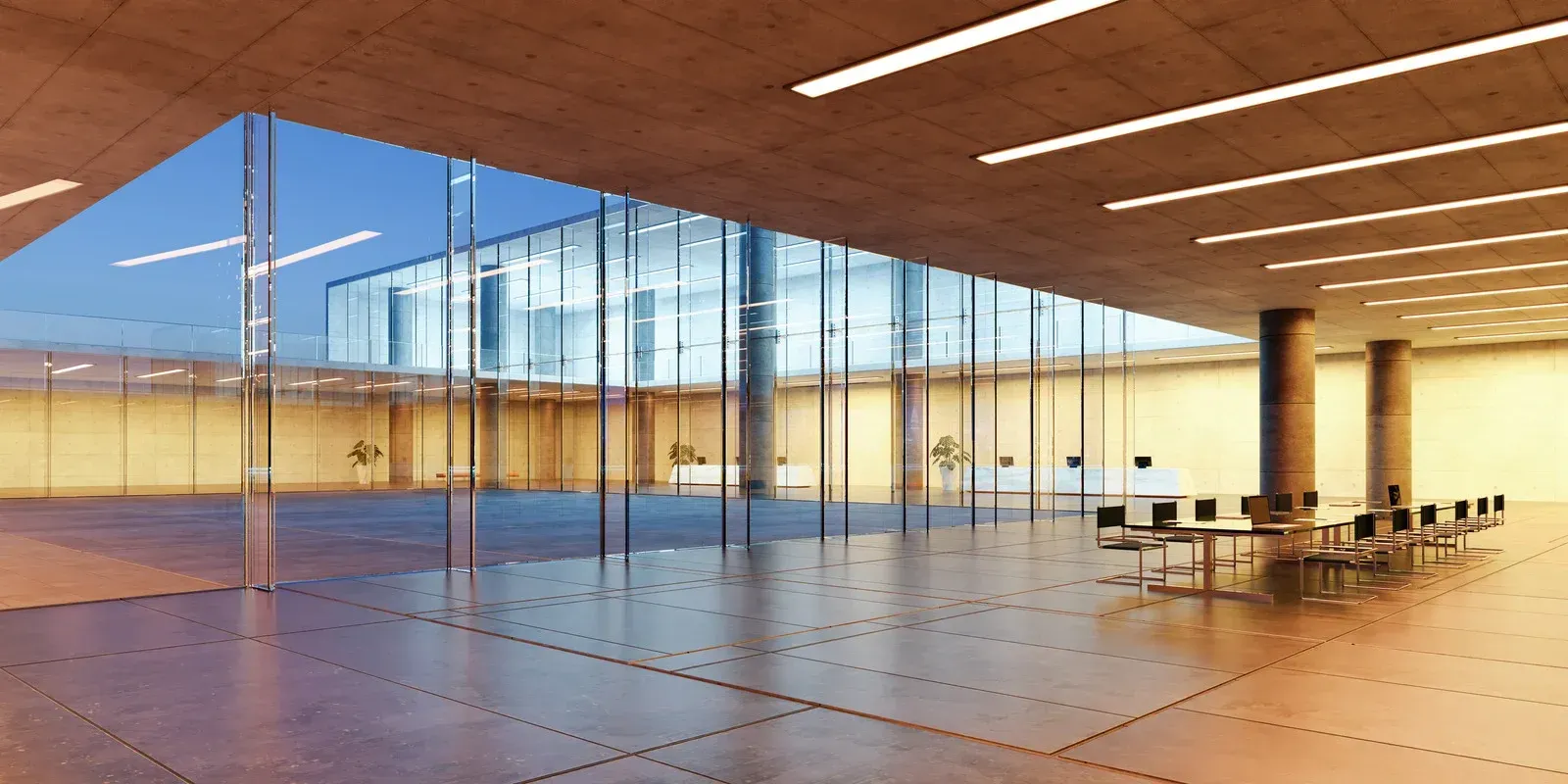 Modern interior of a building with glass walls, concrete ceiling, and large open space.