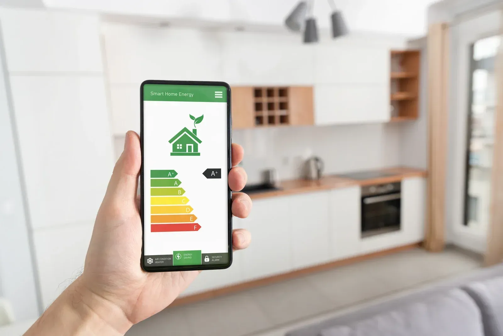 Hand holding a phone displaying a green energy efficiency rating in a modern kitchen.