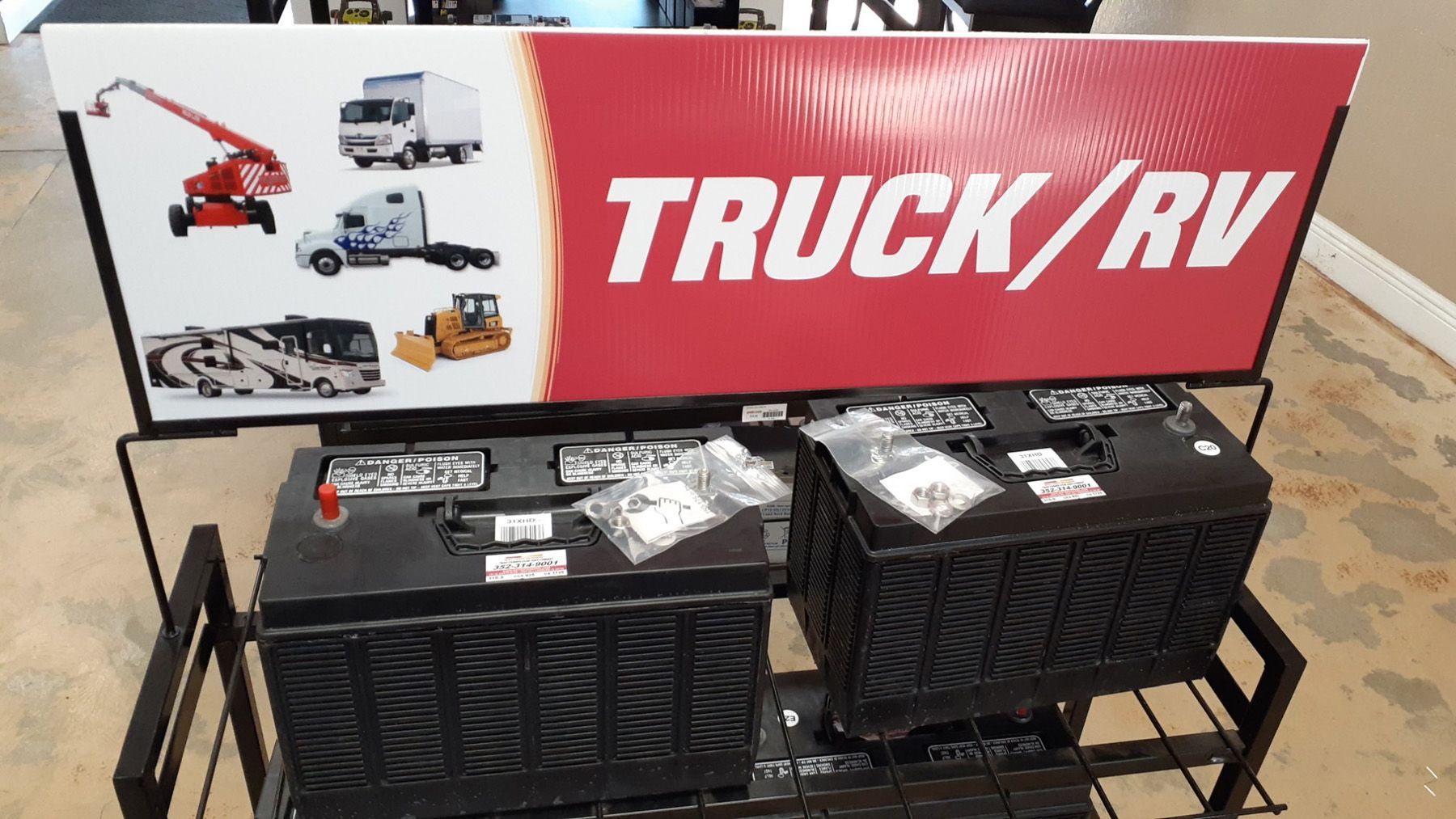 Two black truck/RV batteries on a display shelf, with a red