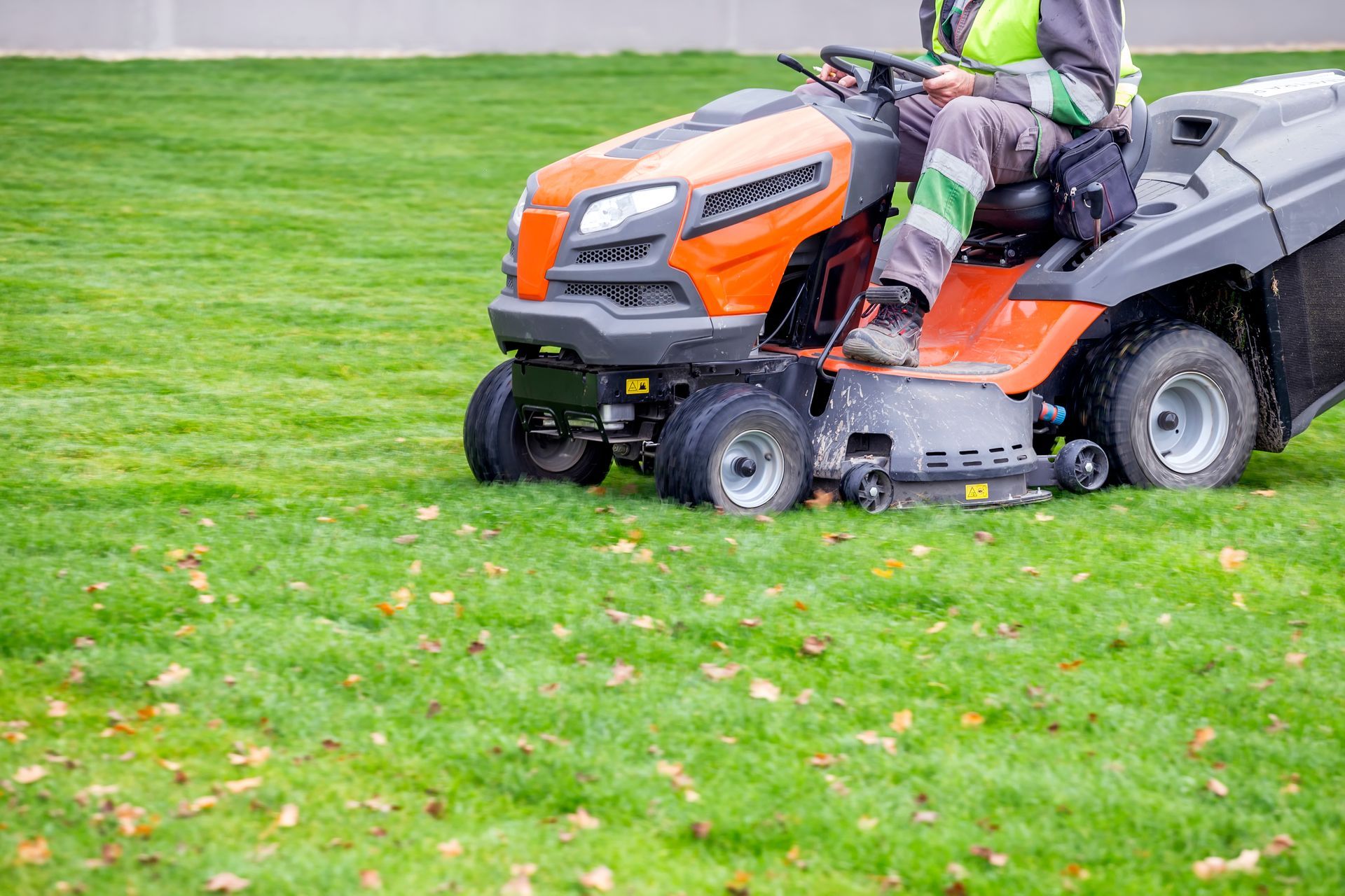 Person inserting battery into a red and black lawnmower on a green lawn.