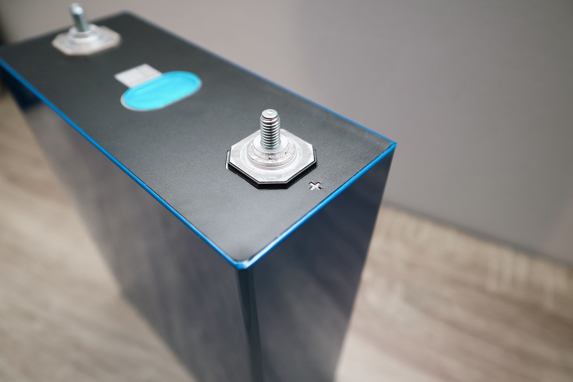 Black lithium-ion battery cell with blue trim and two silver terminals.