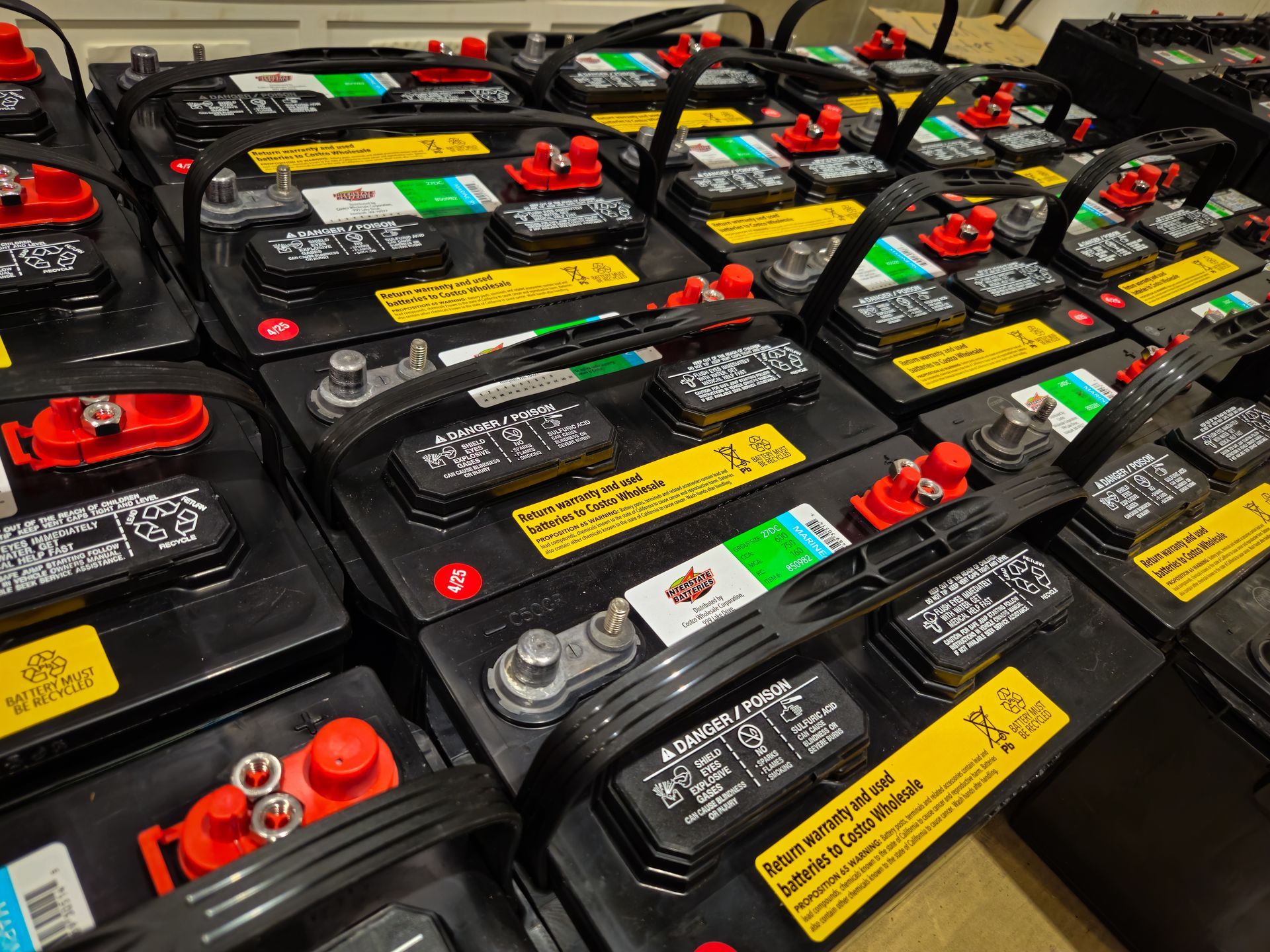 Rows of black batteries with red and silver terminals, connected by black cables, on a light-colored surface.