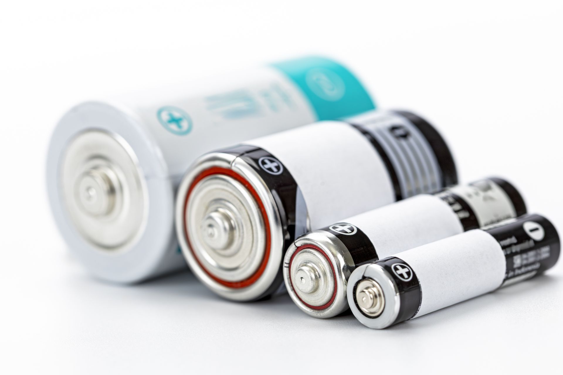 Assorted batteries of different sizes, including AA and C, arranged on a white surface.