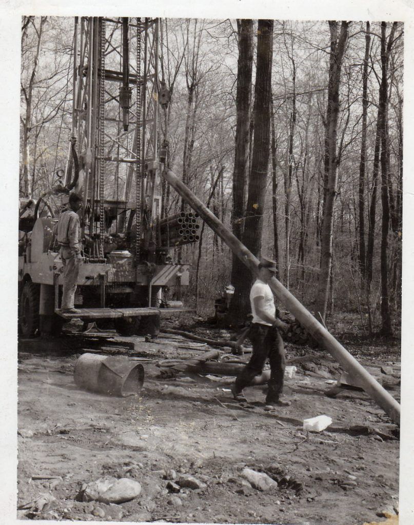 A black and white photo of a man carrying a pipe